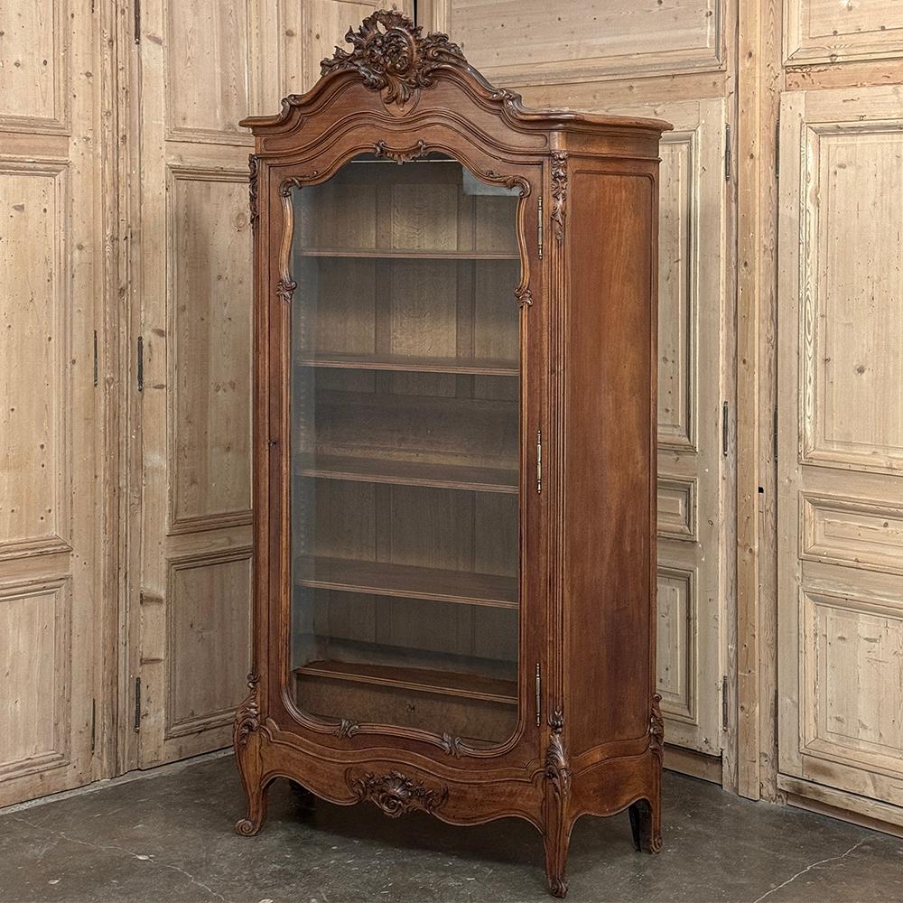Cette armoire d'exposition ~ bibliothèque en noyer serpentin Louis XV du XIXe siècle est une magnifique expression du style rococo, réalisée en noyer français exquis qui est un peu blond, pour une couleur plus claire et plus contemporaine. 