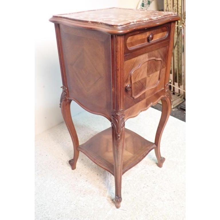 Antique marble topped Louis XV style walnut side table. Features parquetry wood. Nightstand with cabriole legs and fine hand carved detail. Top drawer and cabinet door below. Door opens to reveal white lined marble interior.