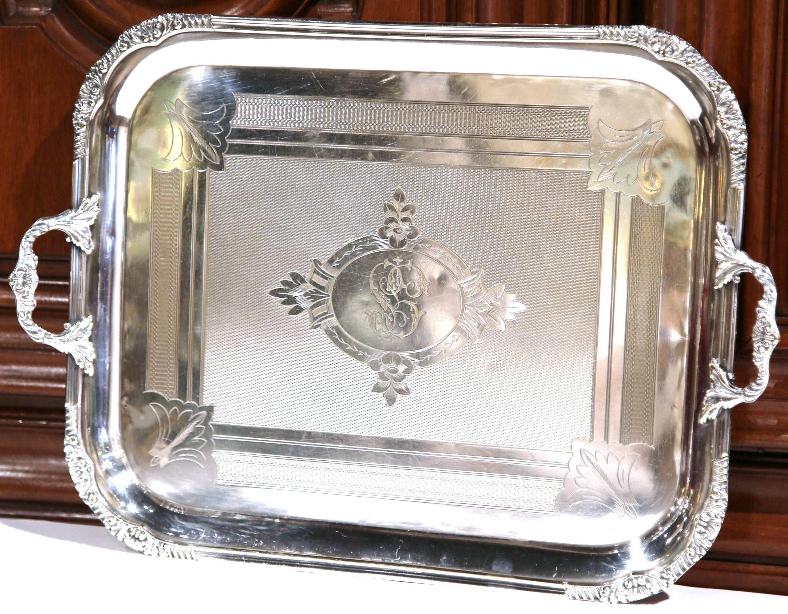 This elegant antique tray was created in France, circa 1880. The silver plated serving piece features two handles with intricate scroll work, repousse motifs in each corner including the traditional Louis XV shell, and an engraved center medallion