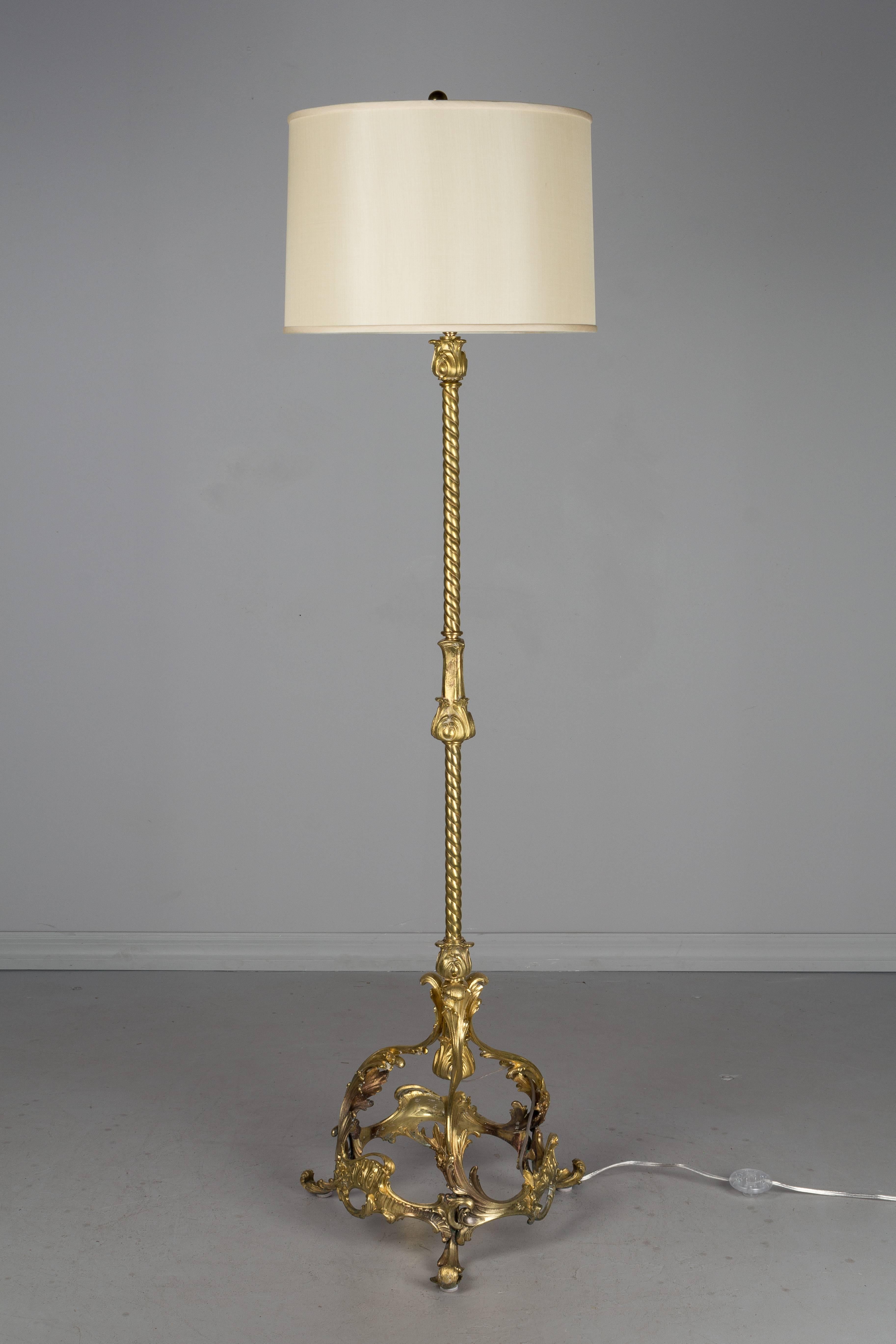 A 19th century French Louis XV style bronze and brass floor lamp. Finely cast fire gilded bronze with heavy welded base. Pole of brass roped tubing with solid cast bronze foliate decorative elements. Rewired with new socket and floor switch. Silk