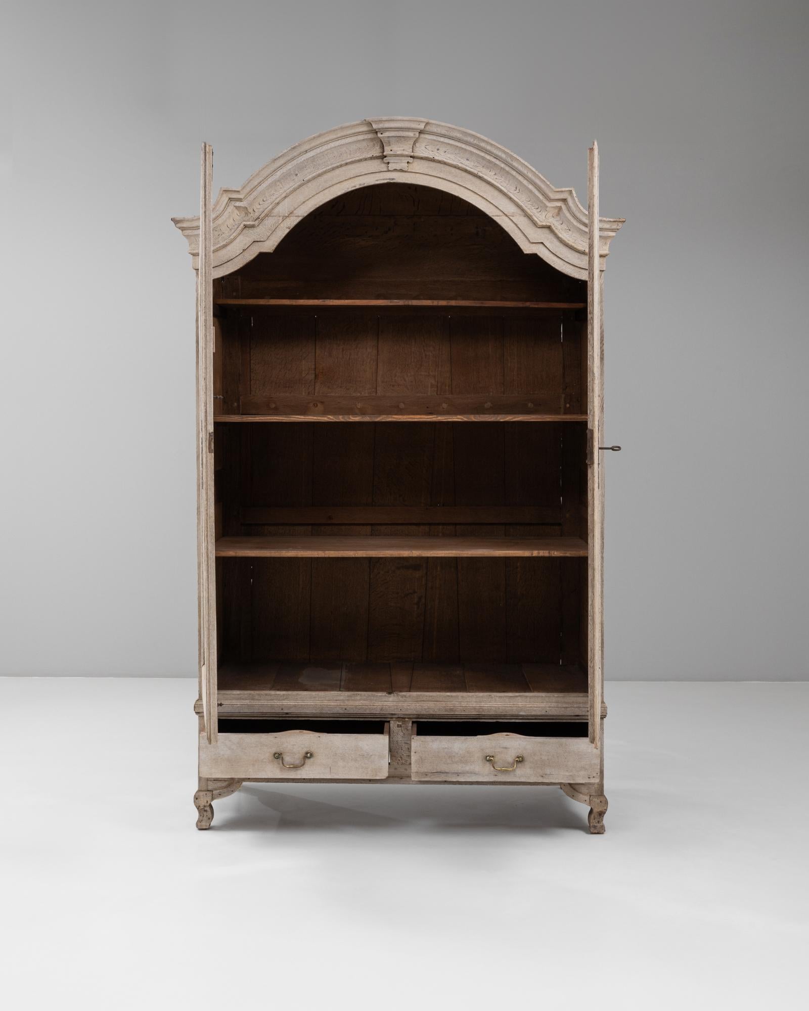 Questo mobile francese del XIX secolo in stile Luigi XV è caratterizzato da un'elegante cornice ad arco e da graziosi piedi a cabriola che ne evidenziano la raffinata silhouette. La finitura in legno sbiancato rivela una patina delicata, bilanciando
