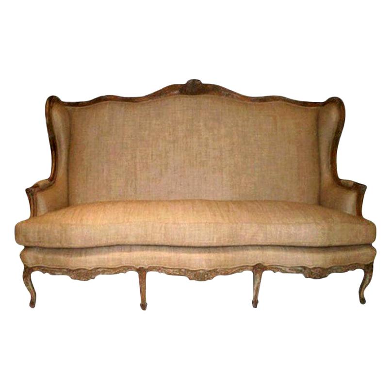 A grand antique French Louis XV style beautifully carved high backed fruitwood canapé or sofa upholstered in oatmeal linen. Underside of cushion has a small tear that has been patched.
Piece was taken down to frame and professionally upholstered.