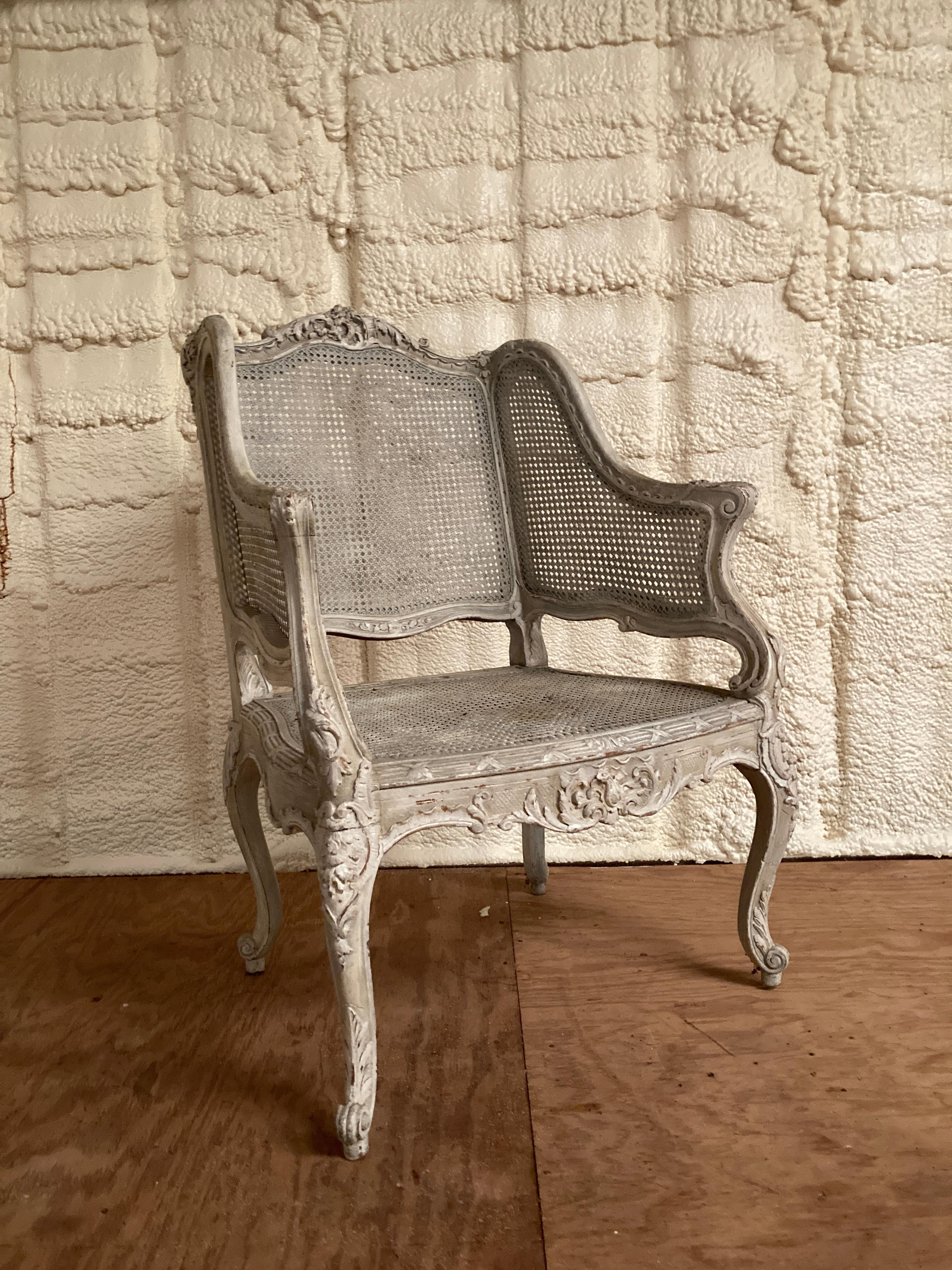 French Louis XV style beautifully carved bergere with caning from the 19th century. This wonderfully carved bergere has an old but later white and gray painted finish and is glazed with a nice patina. The bergere is carved on all four sides making