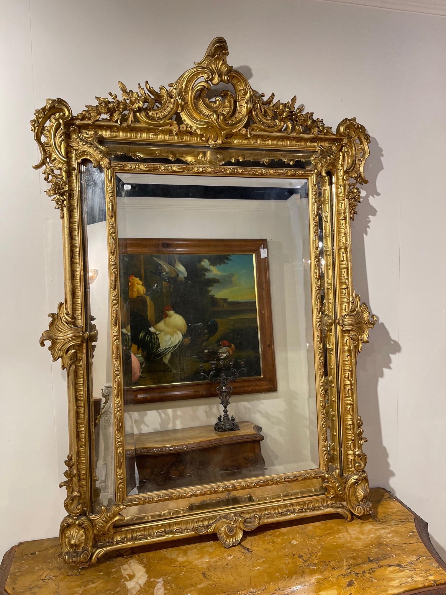 Stunning 19th century French Louis XV style carved and giltwood cushion mirror. Beautiful decorative carvings including an elaborate crest at the top. The piece also has the original beveled glass. Extraordinary!!