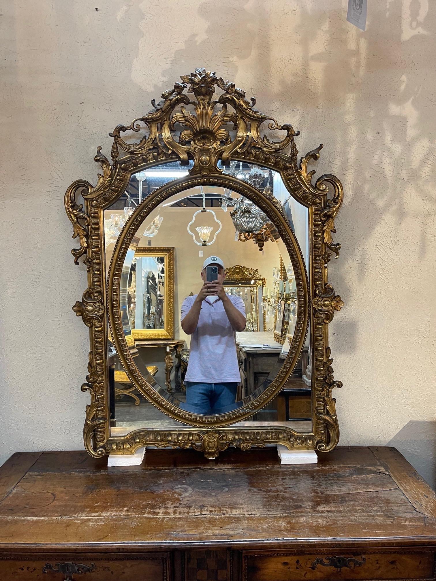 Elegant large scale 19th century French Louis XV style carved and giltwood mirror. Very fine carvings of leaves and flowers and an elaborate crest at the top. Exquisite!