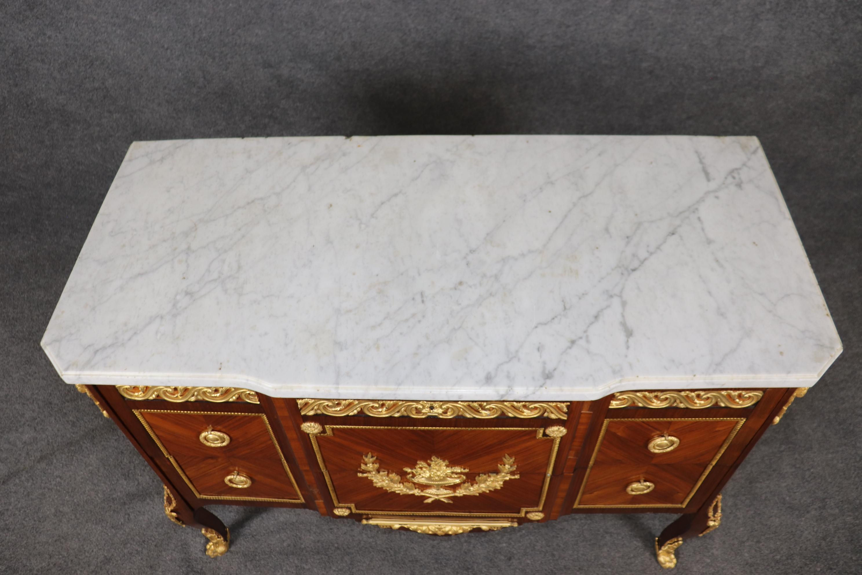 Il s'agit d'une superbe commode, absolument époustouflante, en bronze doré et marbre de carrare. Le style Louis XV incomparable est accentué par des montures en or doré de la meilleure qualité joaillière, représentant des gerbes de fleurs et des