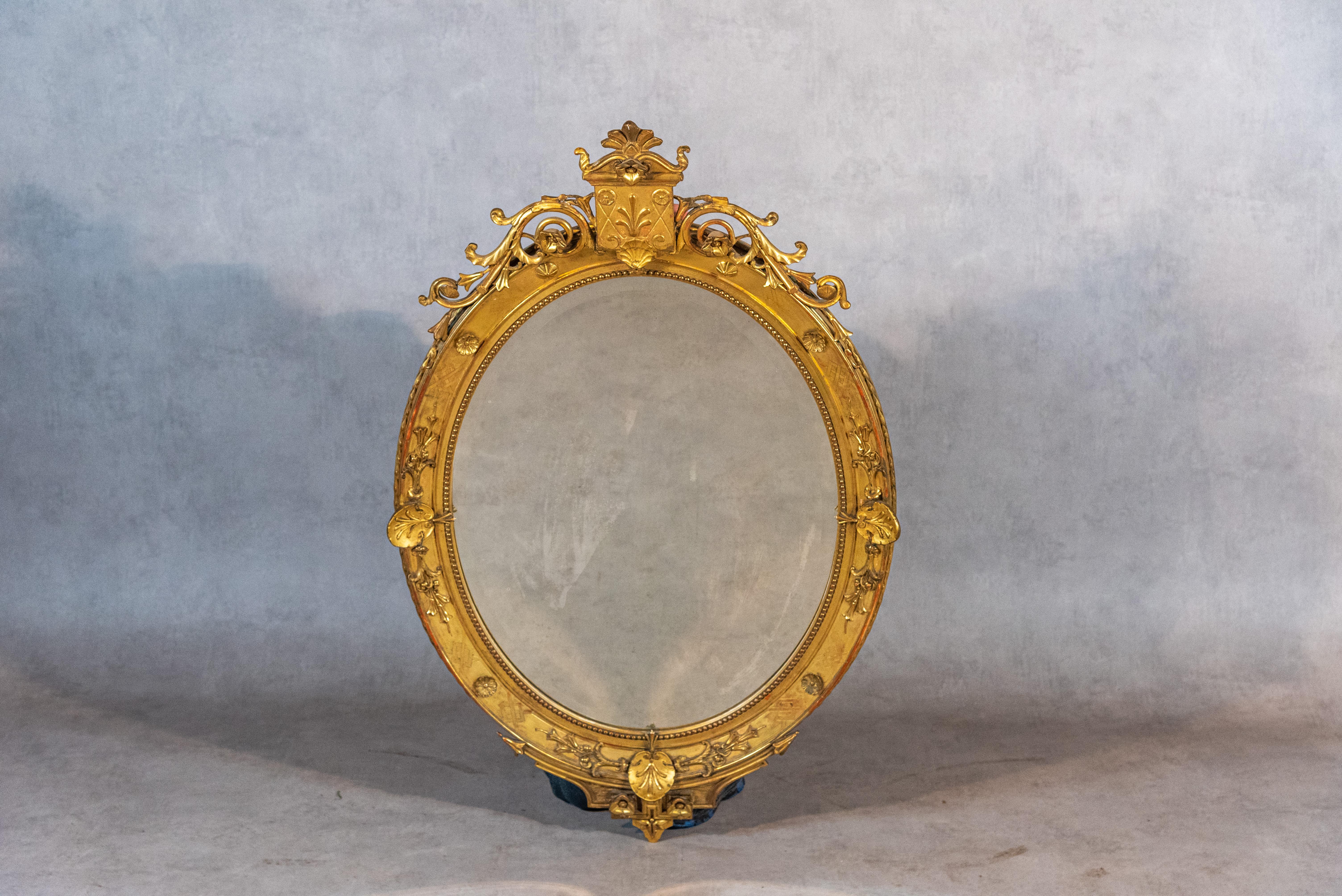 This 18th century French Gilded Gold Oval Mirror of the Louis XV period is a stunning piece that is sure to add a touch of elegance to any interior space. The mirror is a beautiful representation of the Louis XV style, featuring a gilded wood and