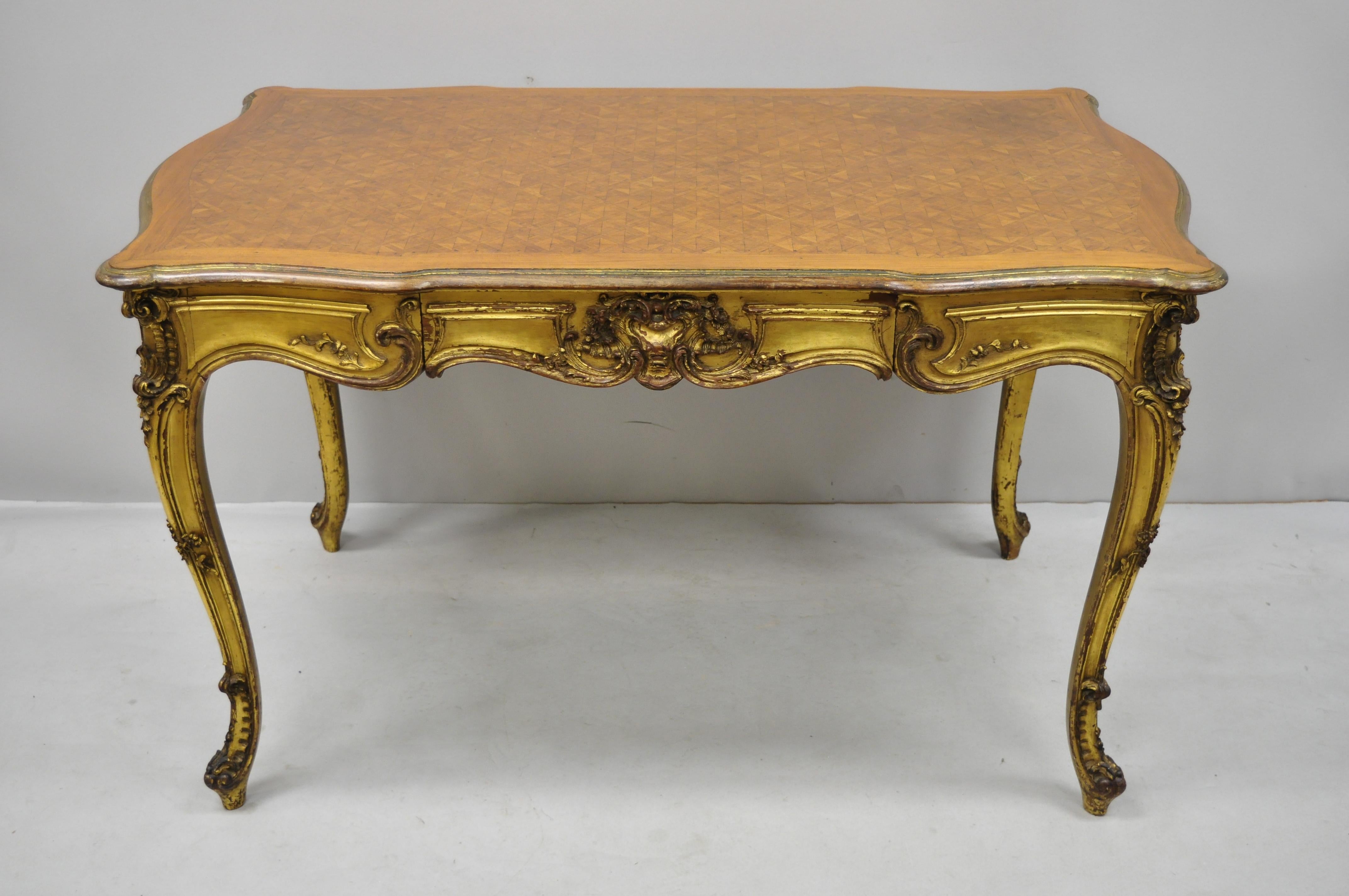19th century French Louis XV style gold gilt small writing desk with marquetry inlaid top. Item features distressed gold gilt finish, shaped top, carvings on all sides, stunning marquetry inlaid top, 1 dovetailed drawer, cabriole legs, very nice