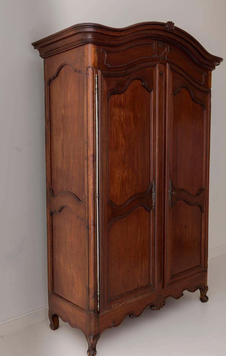 An exceptional early 19th century mahogany wood armoire from the Bordeaux region of France, circa 1810. Arched carved bonnet, two large carved doors, and shaped apron, raised upon cabriole legs. There are three shelves within, the top two are