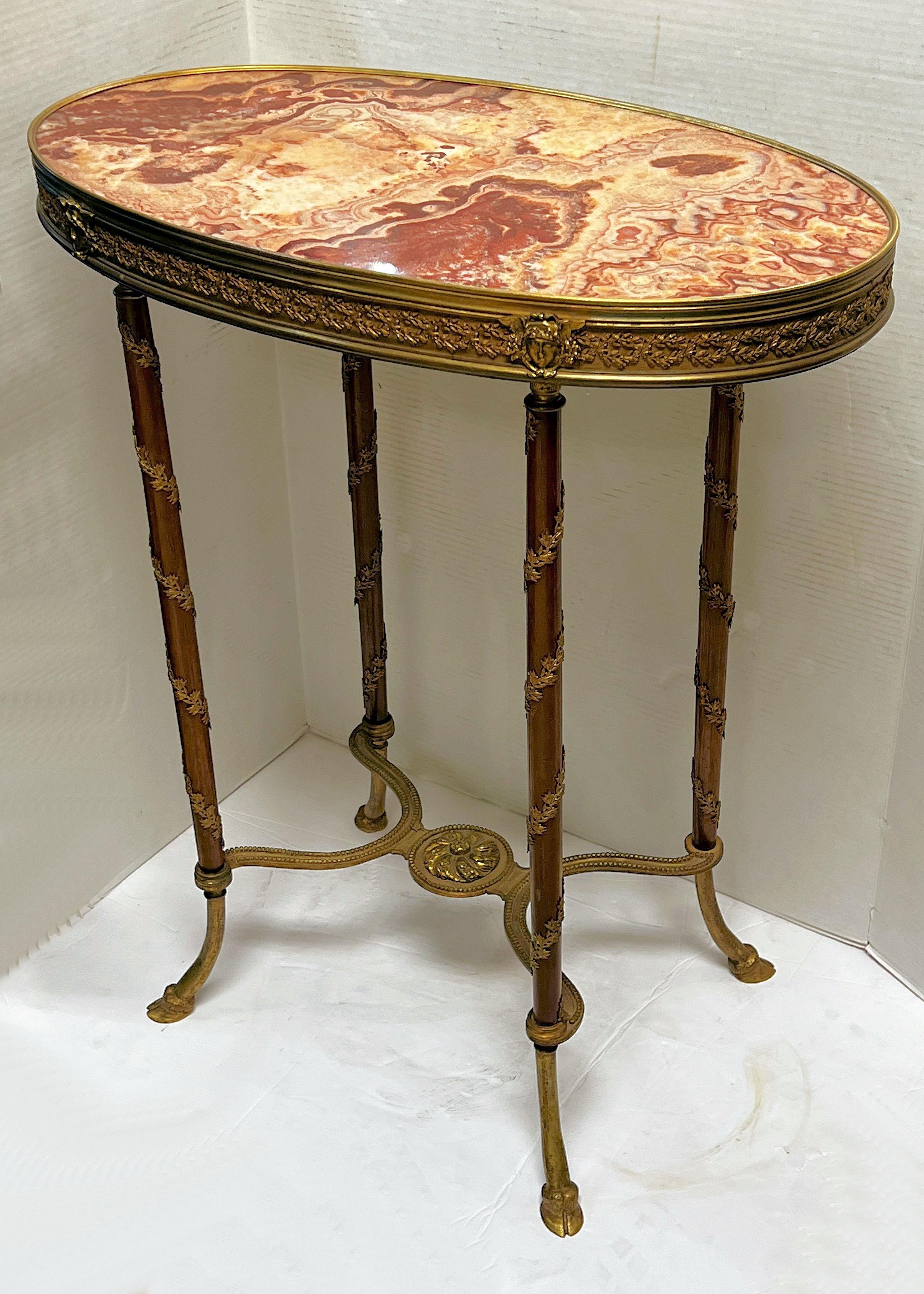 Exquisite French 19 century side table in the Louis XVI style with oval shaped variegated red marble top and frieze, decorated with neoclassical masks and laurel wreath motifs wrapping the legs terminating in hoof style feet.