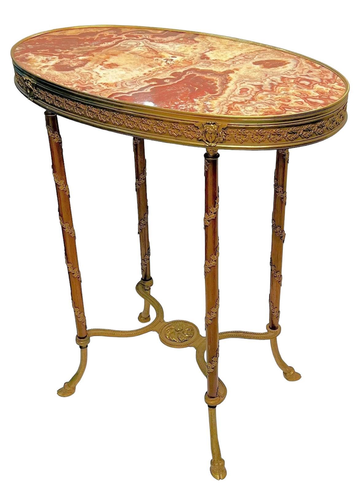 Exquise table d'appoint française du 19e siècle de style Louis XVI avec un plateau et une frise ovales en marbre rouge panaché, décorés de masques néoclassiques et de motifs de couronnes de laurier enveloppant les pieds qui se terminent par des