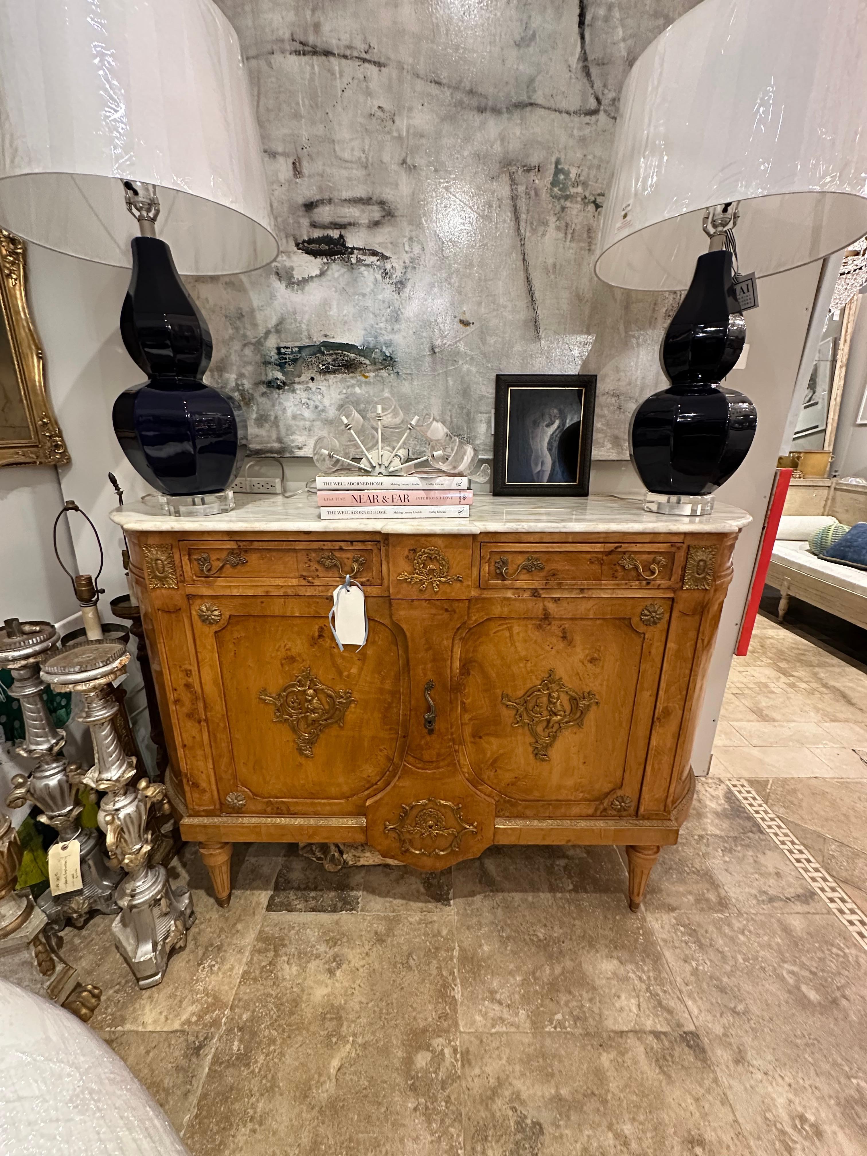 The 19th Century French Louis XV Style Marble Top Sideboard epitomizes the opulence and refinement of the period. Crafted with exquisite attention to detail, it boasts a sumptuous marble top that adds a touch of luxury to any room. The sideboard