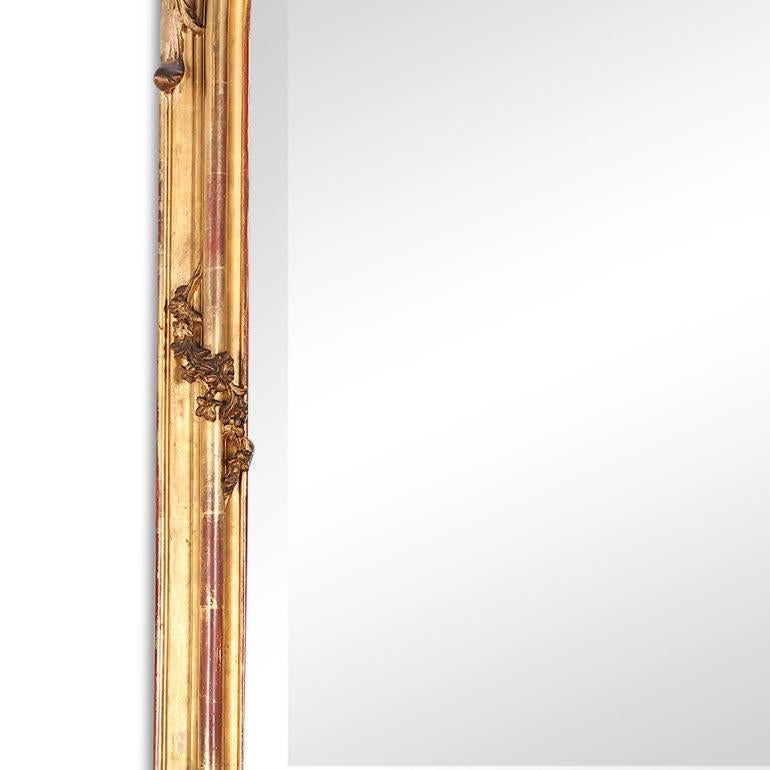 A superb French Louis XV style gilt mirror on a grand scale with an ornate crested top featuring flowers and swags and birds etc. The floral details continue from the top, cascading down each side of this Napoleon III-era piece in spiraling swags.