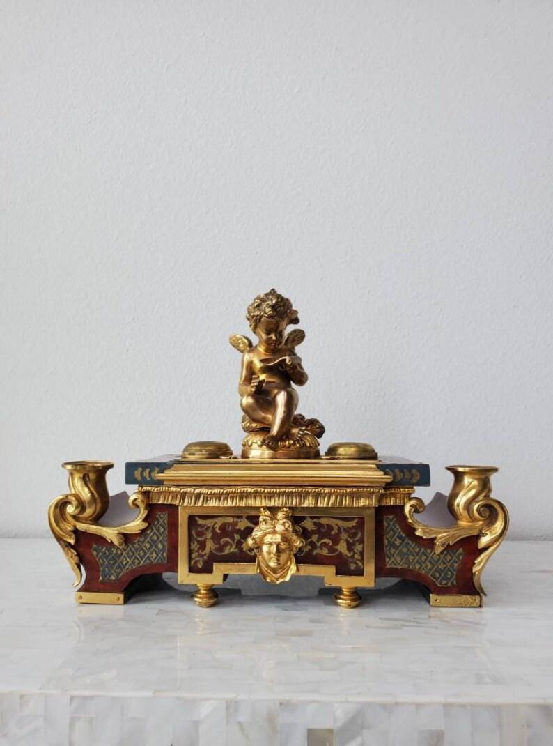 A rare fine French Louis XV style ormolu mounted tortoise-shell finish encrier (desk stand - inkstand) dating to the 19th century, featuring bronze dore sculpture of a winged putto reading from a scroll, flanked by inkwells, pen stands, and recessed