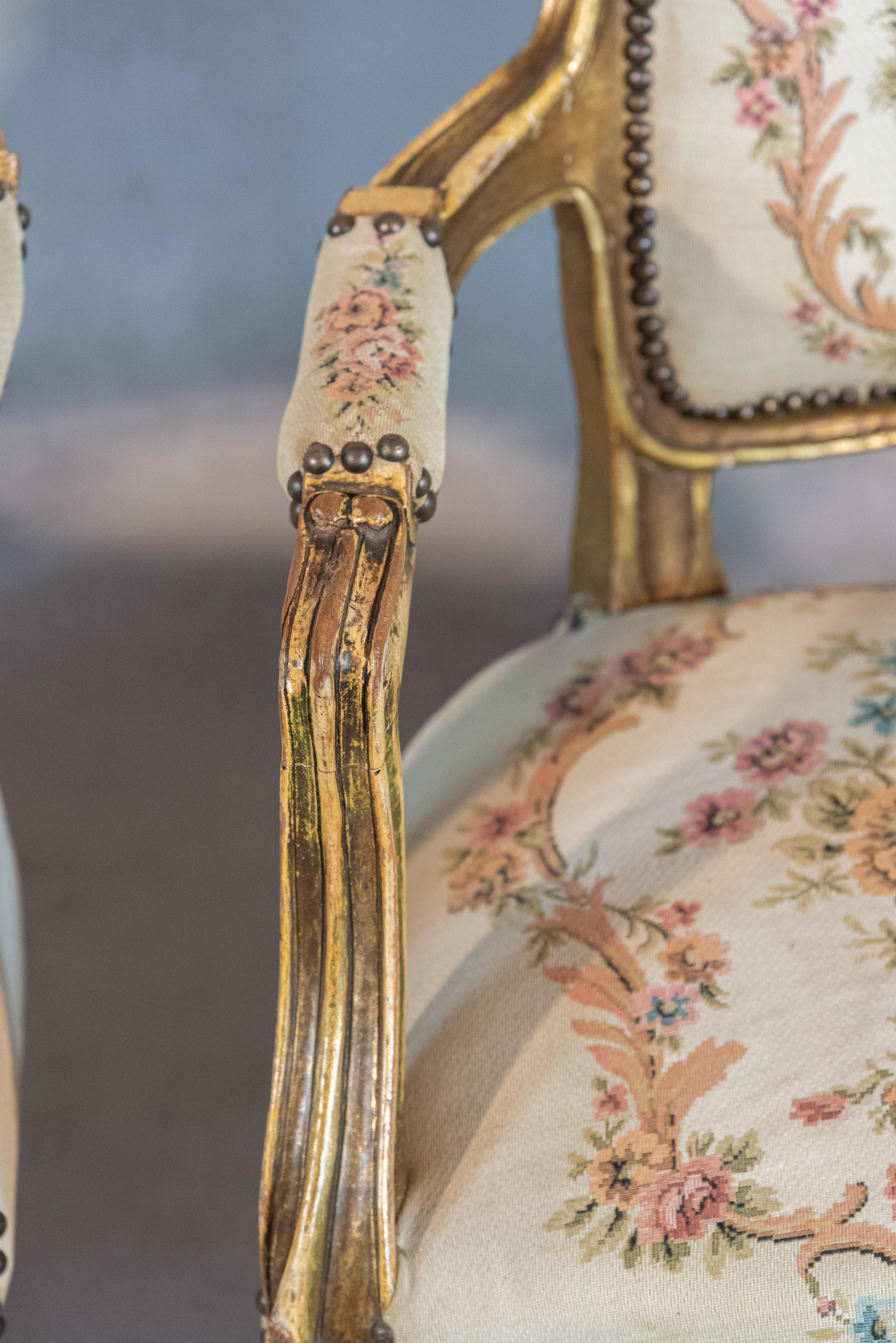 An astounding 19th century French Louis XV Style pair of armchairs. These armchairs are known as “cabriolet” and feature a Romantic depiction on the backrests and beautiful floral motifs on the seating. The contrast between the solid frame and the