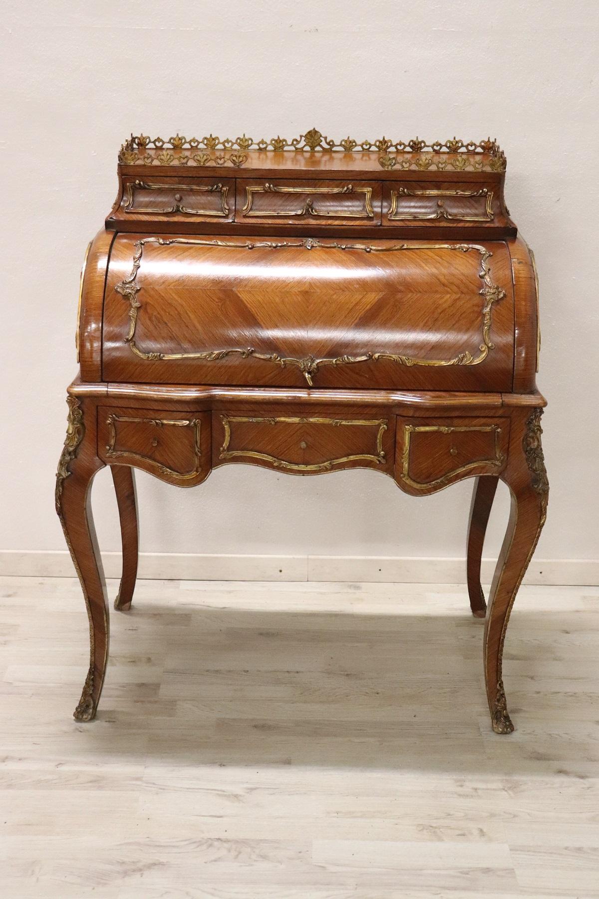 Spectacular antique French desk in precious rosewood. The line is typical of the Louis XV style with elegant wavy legs. Rich decoration in finely chiseled gilded bronze makes this desk even brighter. The front with rounded shutter when it is opened