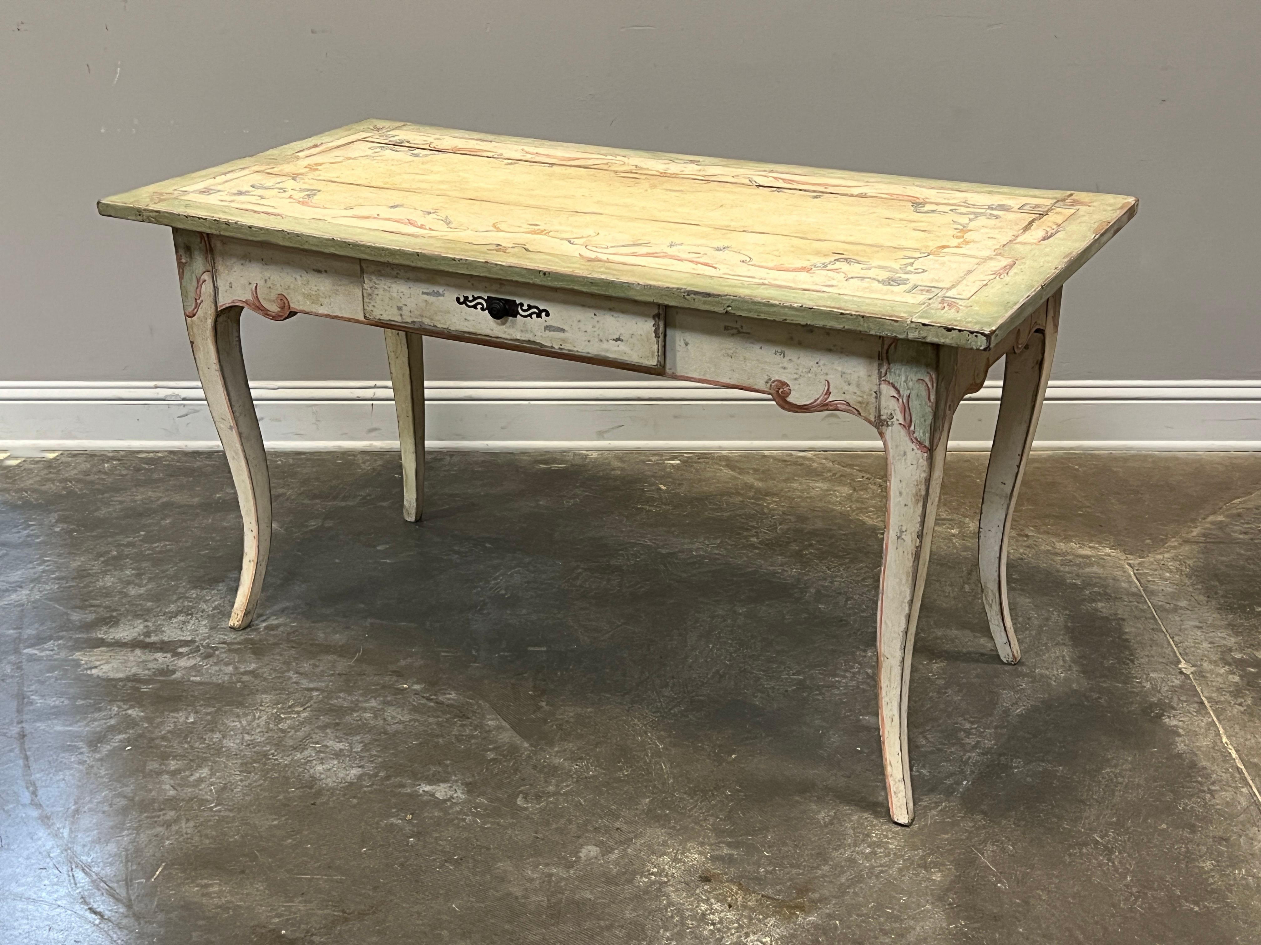 Lovely early interpretation of Louis XV with graceful chambered legs and one drawer. Painted in delicate scroll work, the table is antiqued to a finish appropriate and relative to the age of the desk. Major color is a soft green with cream secondary
