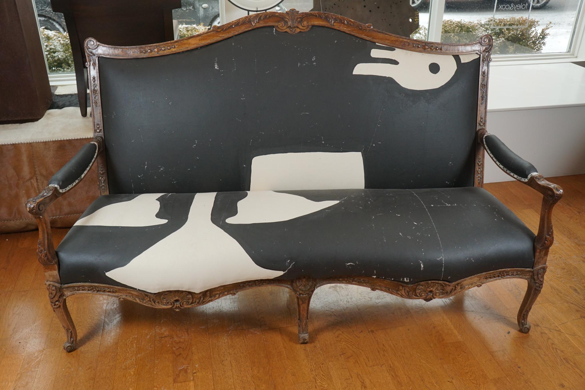 An elegant 19th century French Louis XV style settee, with a shaped crest and skirt. slightly distressed, this settee is carved overall with shells and acanthus leaves. Its unique and incredible upholstery is from a theater set back drop.