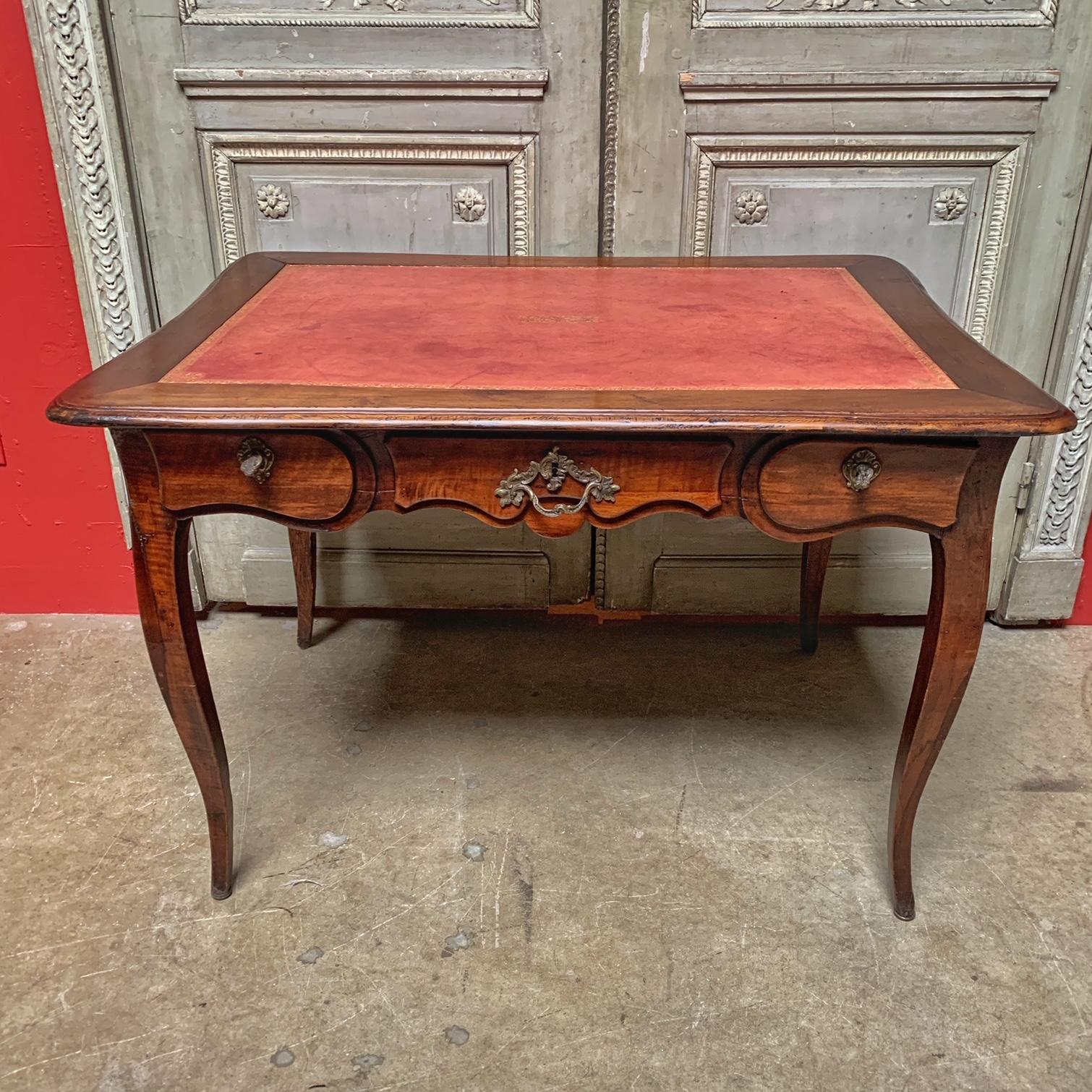 A Louis XV style French writing table in walnut with bronze hardware and an antique red leather tooled top.
This beautiful table is probably from the Lyon region of France and is from the 19th century. It would be a great side table as well as a