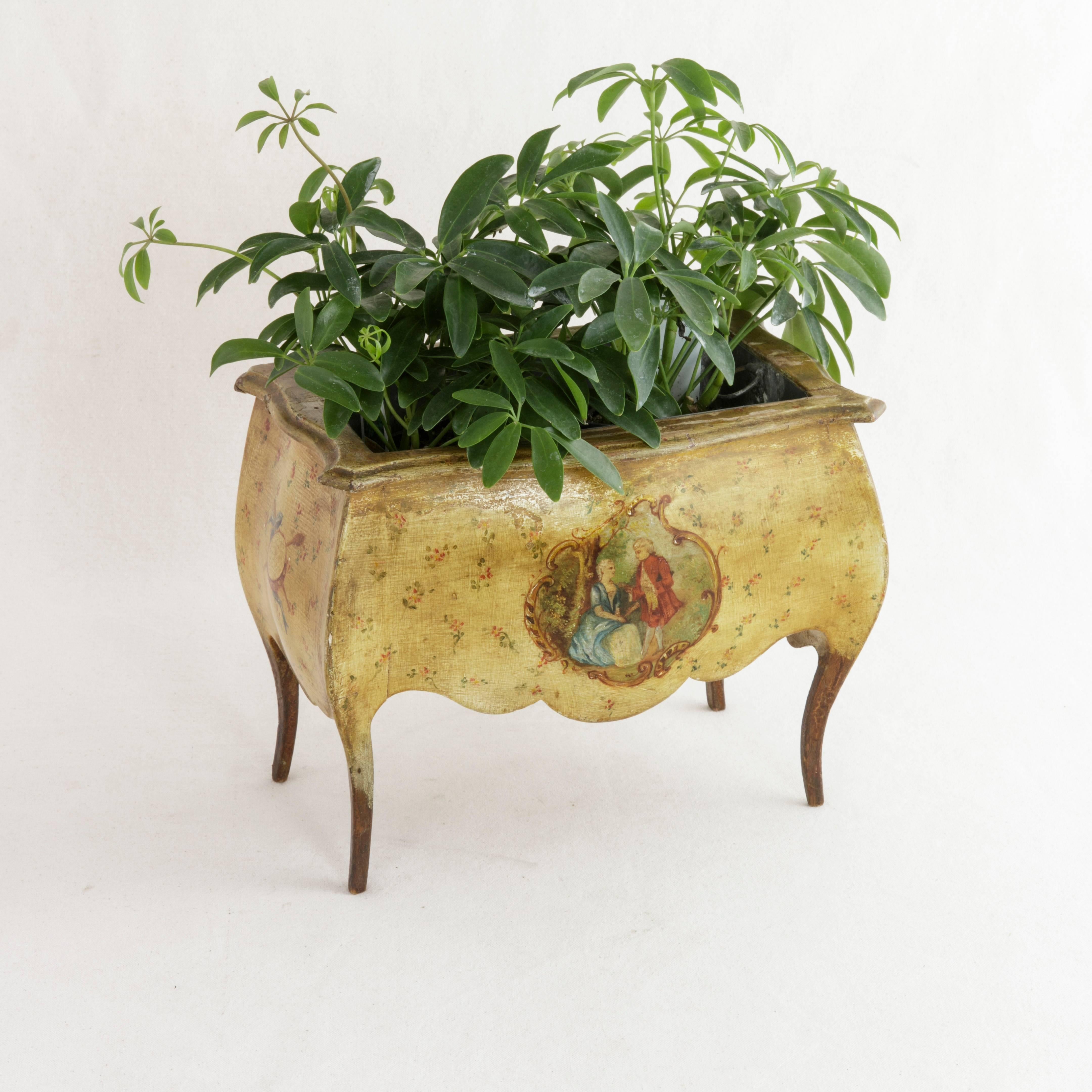 This late 19th century hand-painted tole jardinière or cachepot stands gracefully on Louis XV cabriolet legs and still holds its original removable zinc liner. Tiny flowers on a yellow field provide the backdrop of an 18th century courting scene