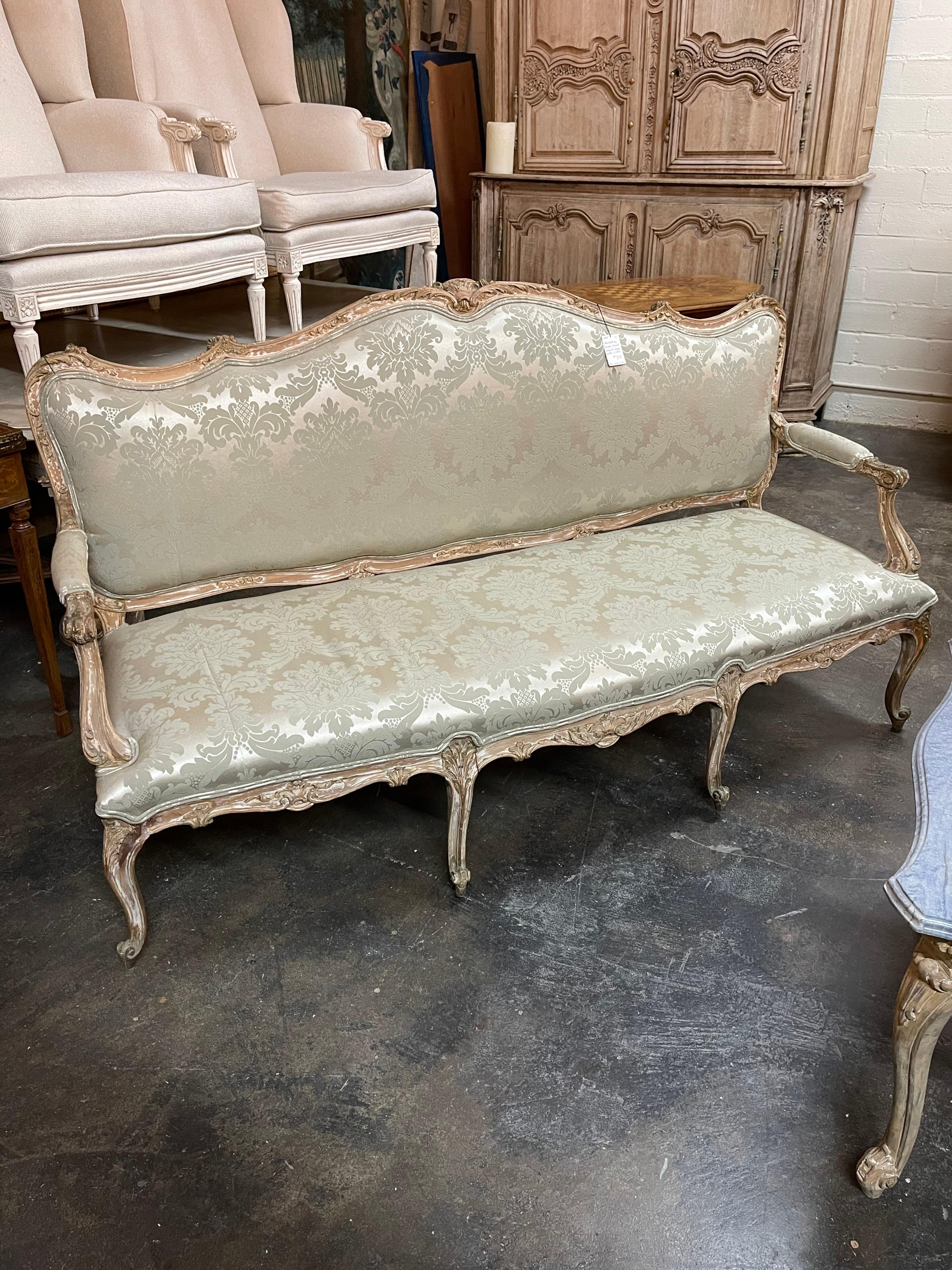 Fine quality and very elegant 19th century French Louis XV style settee or sofa with a shaped crest and skirt. Expertly hand-carved overall with shells and acanthus leaves. Upholstered in a superb damask fabric. The entire on graceful cabriole legs
