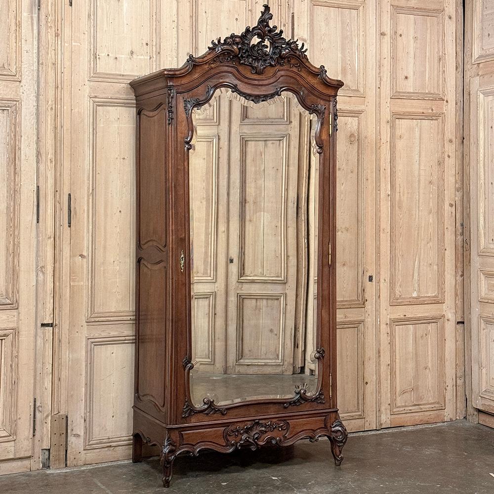 19th Century French Louis XV Walnut Armoire is a sublimely stately expression of the refined Rococo style performed by master artisans from sumptuous French walnut.  The casework features a timeless design fitted with a full length hand-beveled