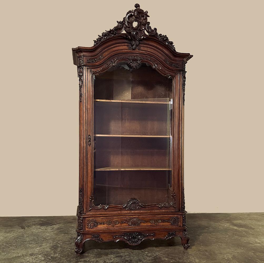 19th century French Louis XV walnut display Armoire ~ Bookcase is a majestic example of fine craftsmanship, executed in what experts consider the finest indigenous wood ever available from the continent of Europe! The boldly arched crown is