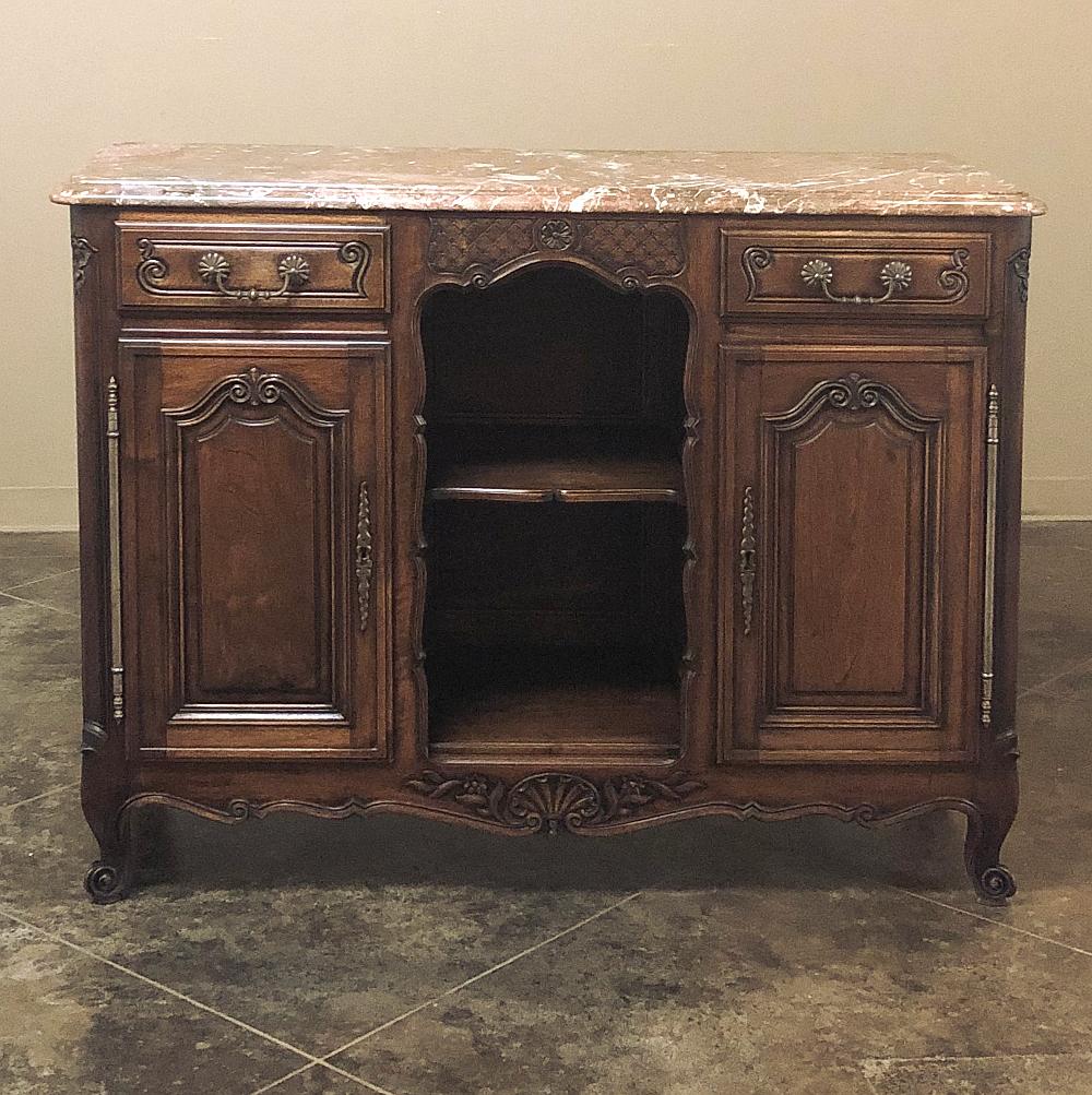 19th century French Louis XV walnut marble-top buffet features subtly curvaceous naturalistic lines accented with shell and foliate carvings, with an interesting design that includes two drawers above two cabinets flanking an open display section