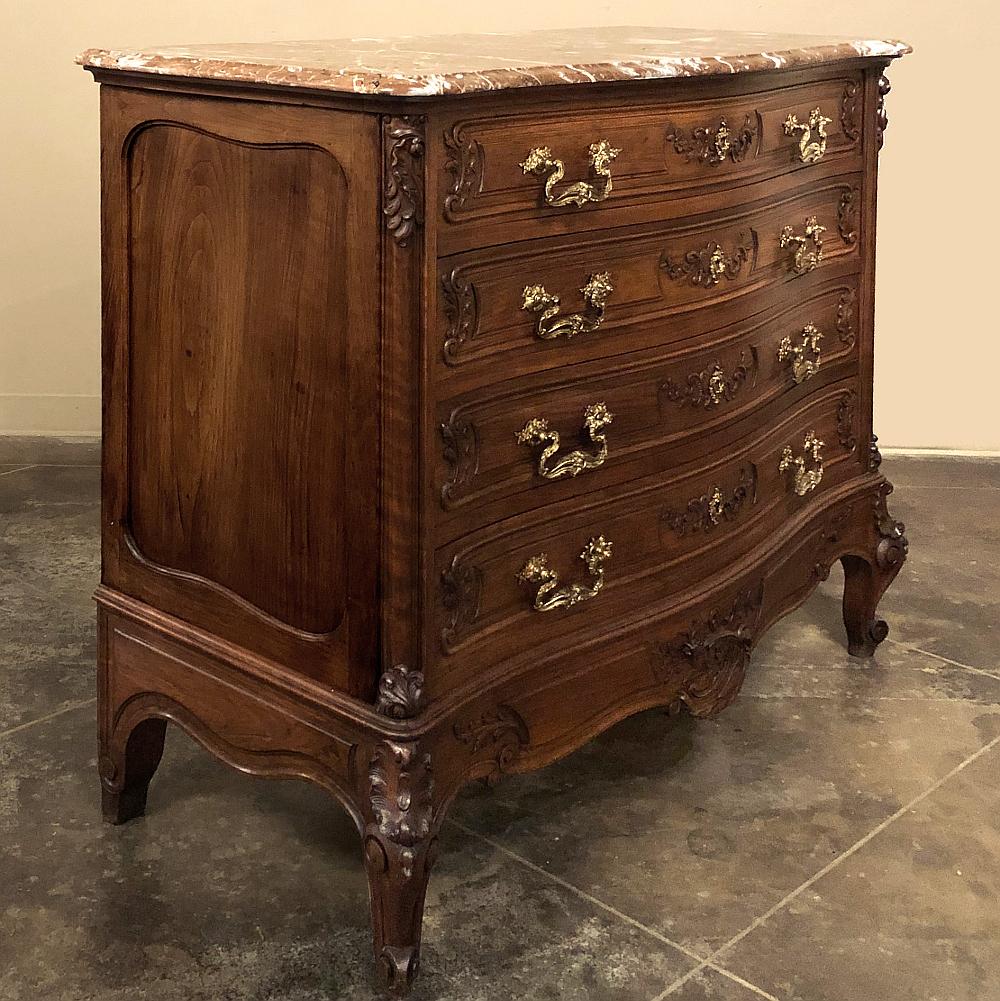19th century French Louis XV walnut marble top commode is a rare find indeed! Artfully hand-crafted from sumptuous select French walnut, it features a subtle bowed front that is lavished with asymmetrical carvings of natural forms including foliates