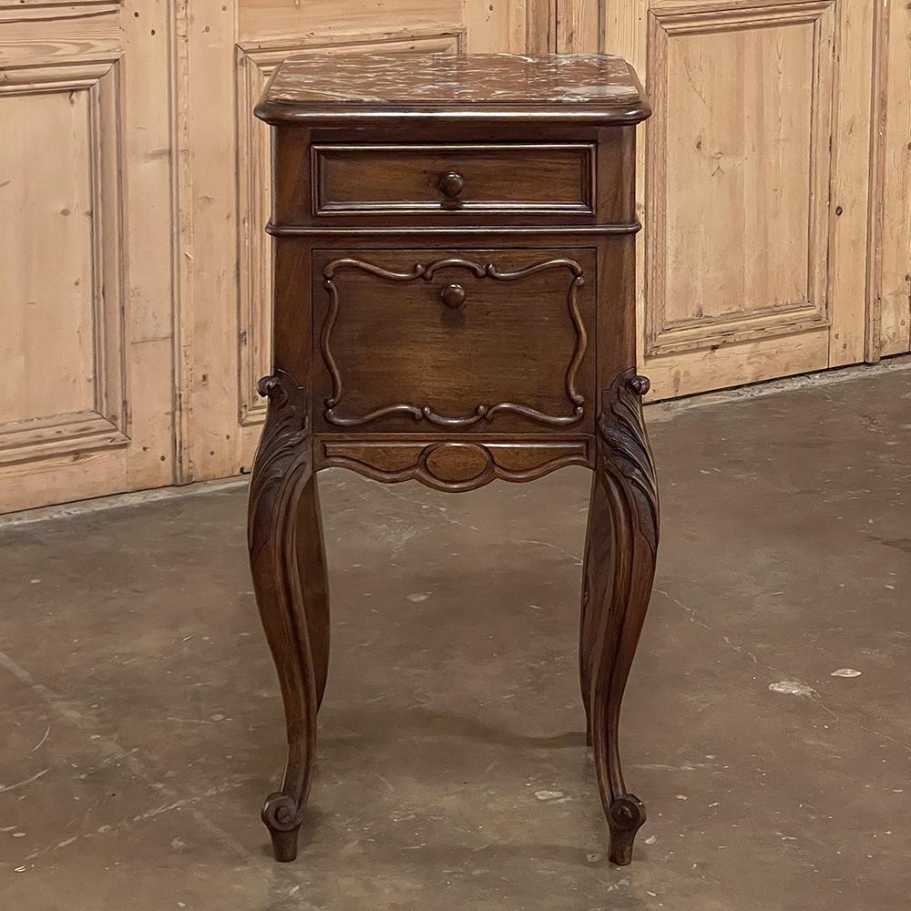 19th century French Louis XV walnut marble top nightstand is a classic example of the genre, rendered in sumptuous French walnut and topped with beautifully veined marble for a timeless effect. The front facade has a beautiful contour enhanced by