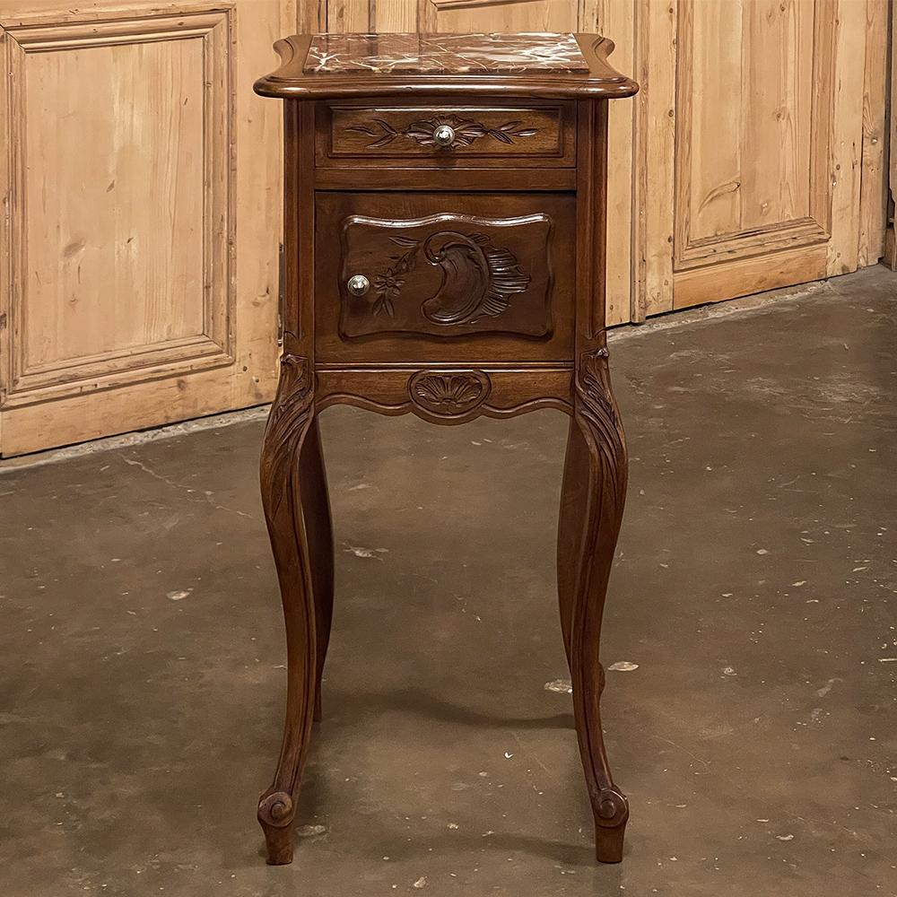 19th Century French Louis XV walnut marble top nightstand is a classic example of the genre, rendered in sumptuous French walnut and topped with beautifully veined marble for a timeless effect. The front facade has been beautifully carved directly