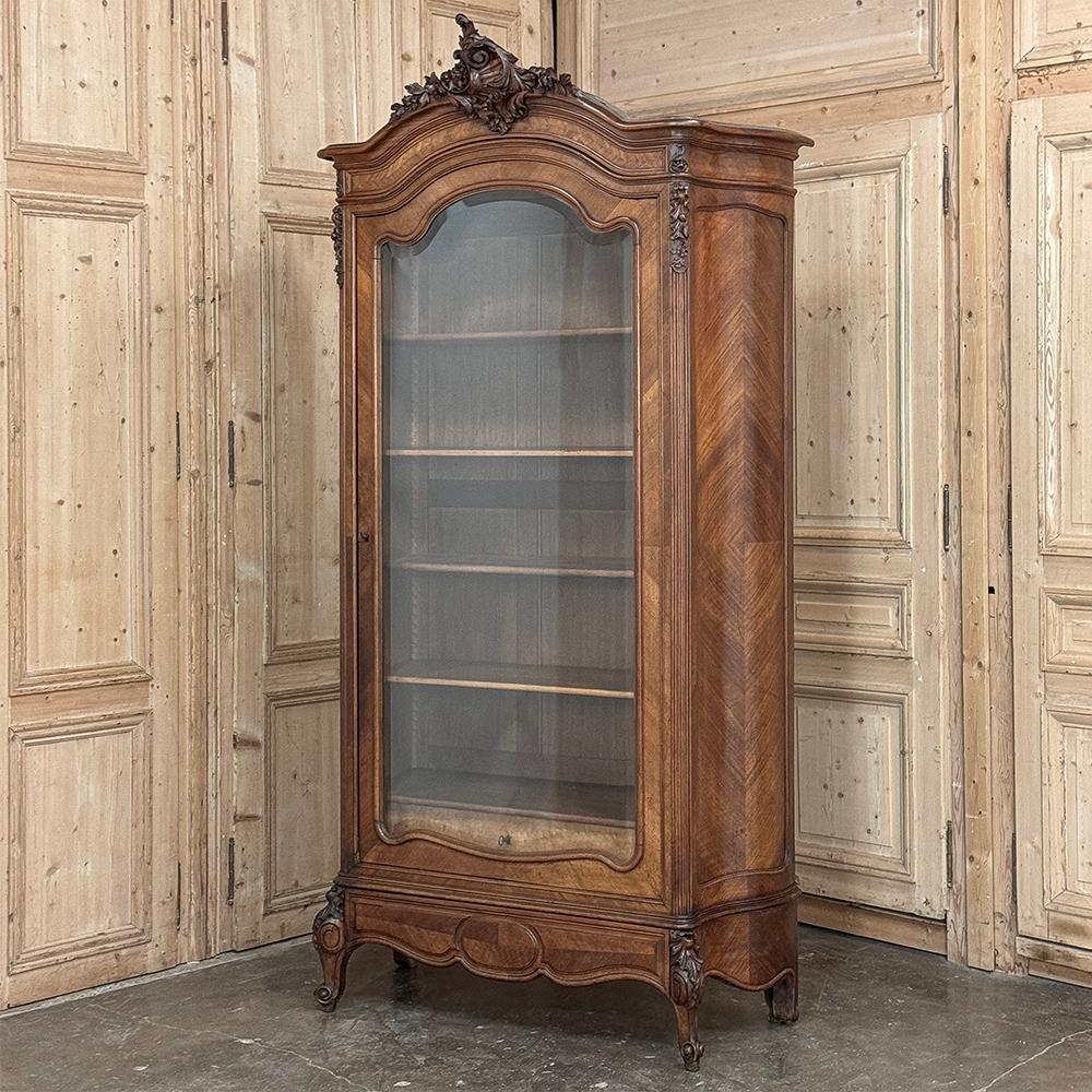 Armoire d'exposition en noyer serpentin Louis XV du 19ème siècle ~ Bibliothèque est un exemple étonnant d'artisanat et de design !  L'ébénisterie présente des côtés serpentins, une couronne audacieusement arquée et un tablier en arbalète avec des