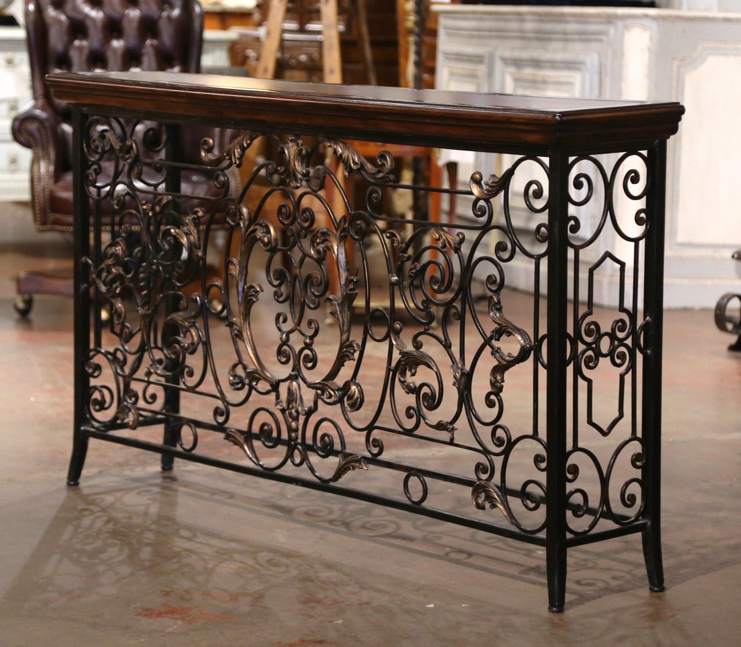 Forged in France circa 1880, the antique console table base stands on curved front legs connected with an all around bottom stretcher. Long and narrow, the Louis XV style table features intricate scrolled decor on all three sides, embellished with a