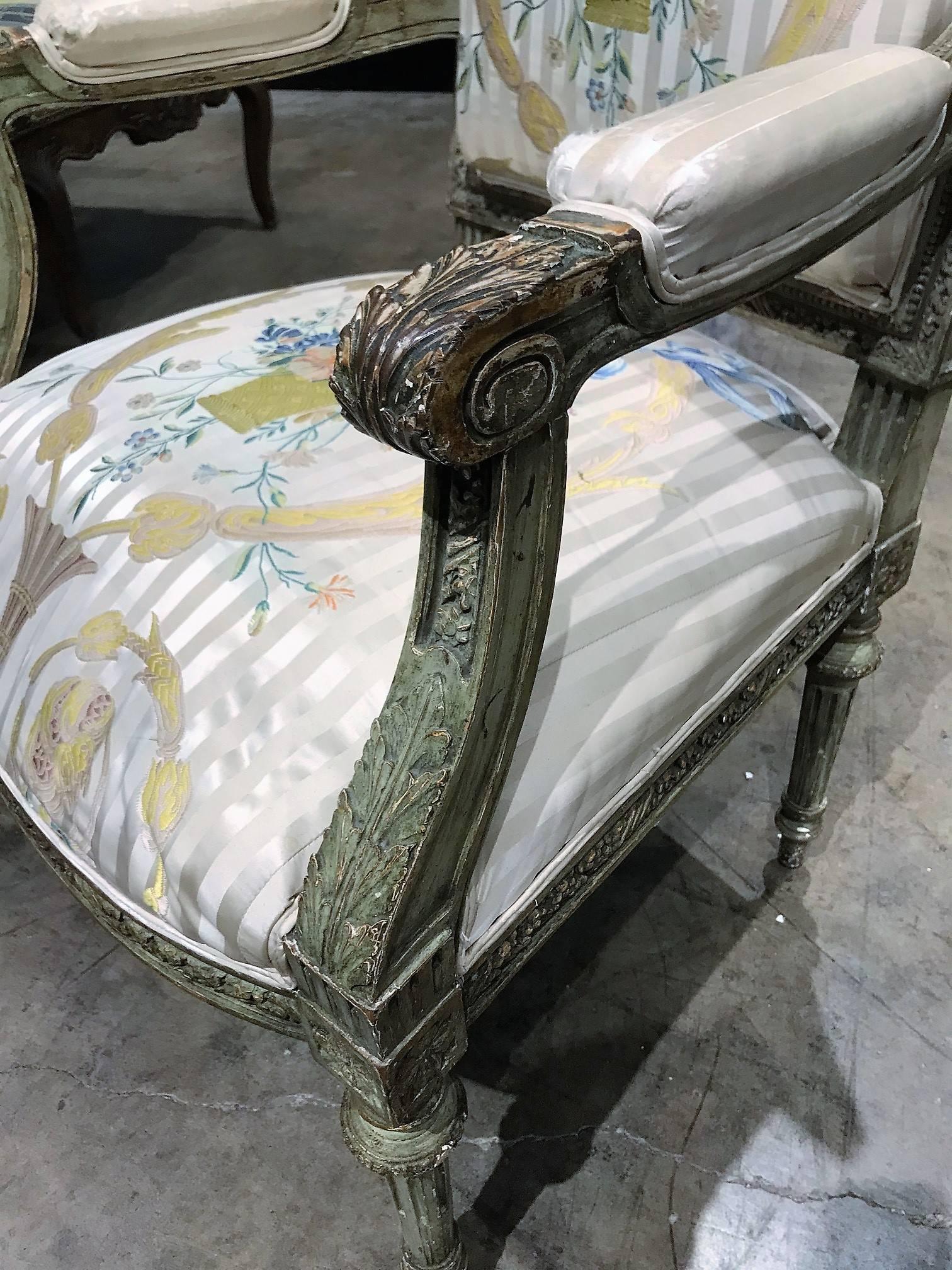 Fine quality and elegant 19th century French armchair with old painted finish and high-end silk upholstery decorated with ribbons and basket with a colorful floral bouquet. The frame superbly carved with acanthus, the crest hand-carved depicting a