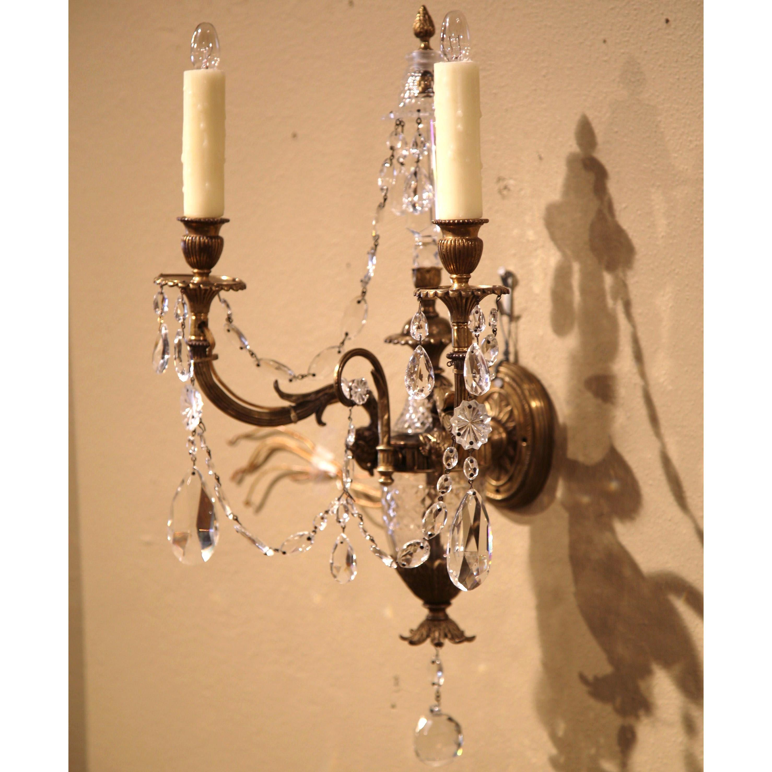 Light up your home with this elegant antique wall light from France, circa 1880. The sconce features two intricate bronze arms decorated with ram heads, cut-glass swags and other beautiful glass decorations. The fixture has new wiring dressed with