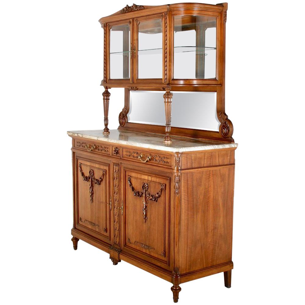 A fine-quality French Louis XVI buffet hutch in walnut, the base with two doors embellished with carved swags below two drawers, the whole raised on fluted turned tapering legs. A marble top serving surface below the upper display cabinet which