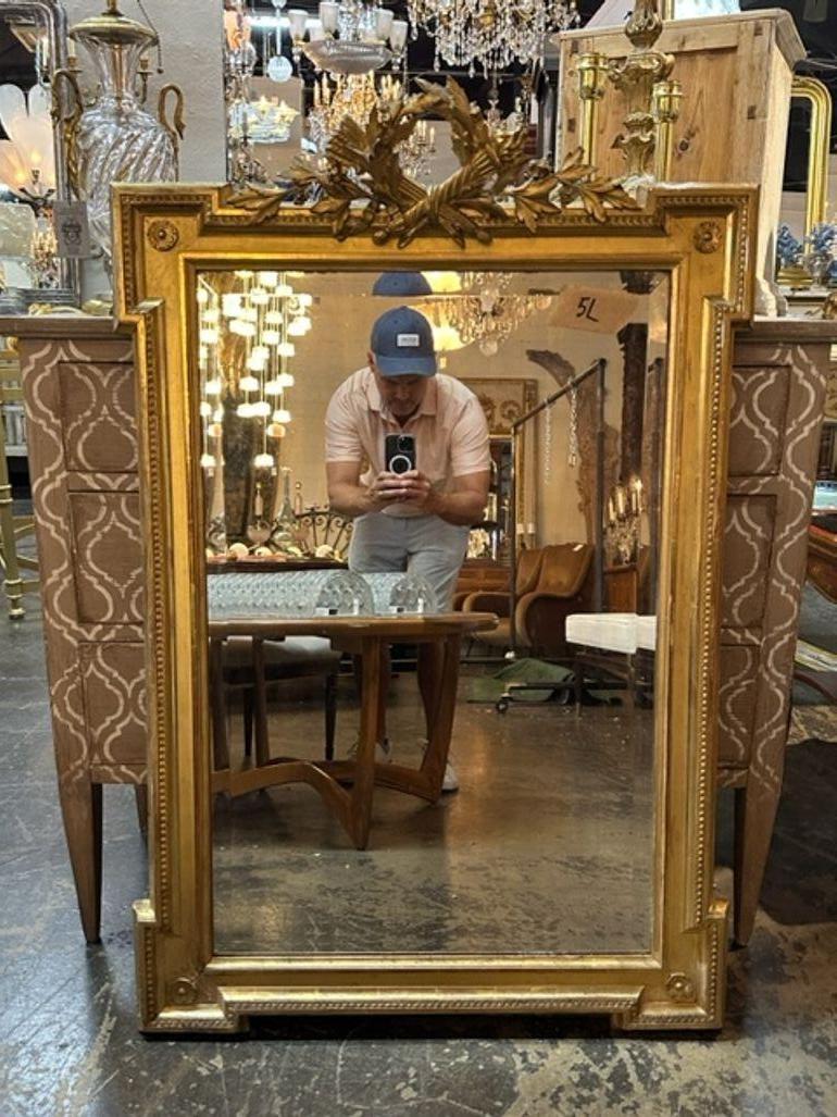 Elegant 19th century French Louis XVI carved and giltwood mirror. Featuring a beautiful carving of leaves, stalks of wheat and a torch at the top. Exceptional!!