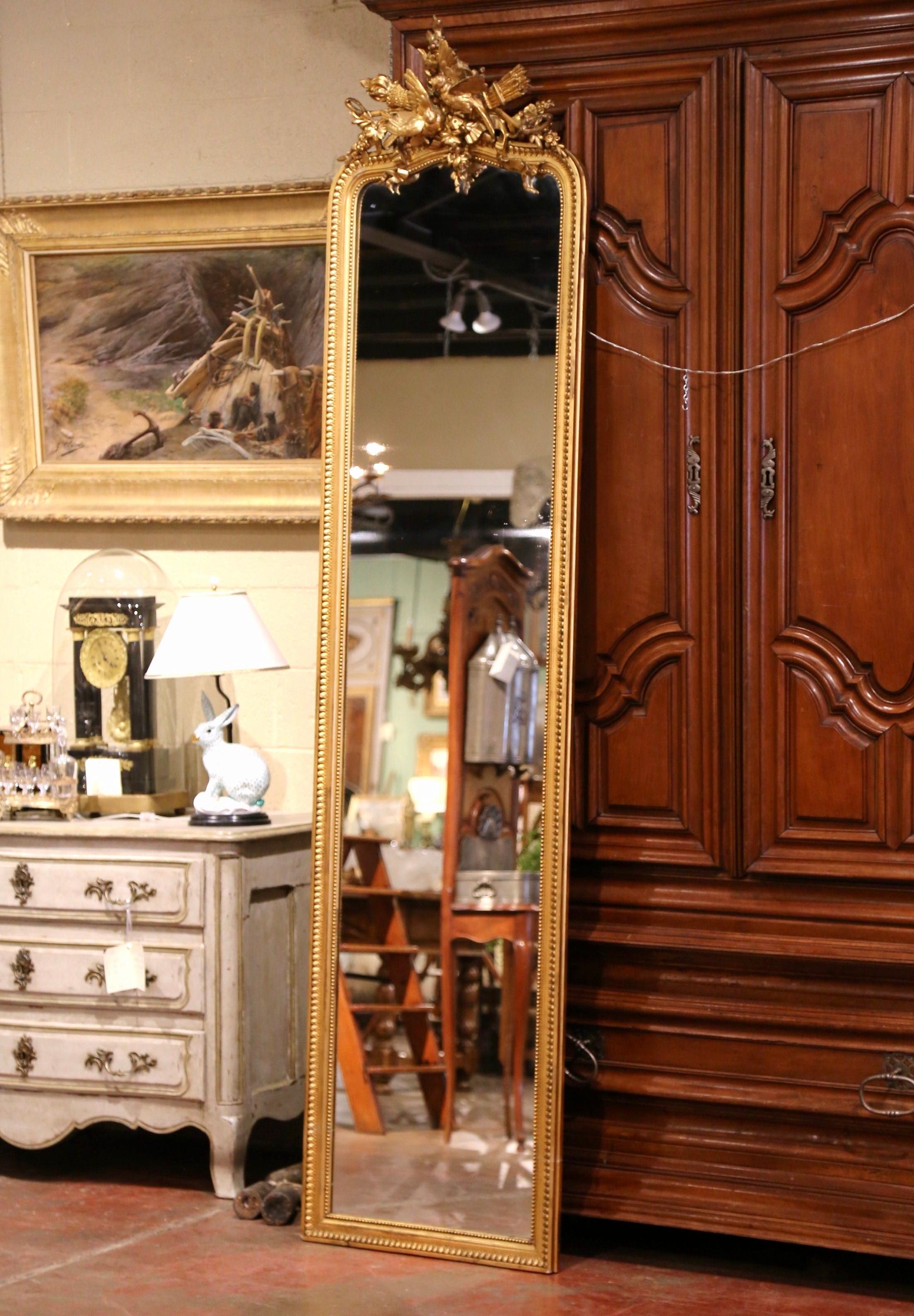 Almost 9 feet tall, this monumental antique mirror is a one of a kind! Crafted in Paris, France circa 1870, the floor mirror with arched top is decorated with high relief hand carved bird sculptures at the pediment, and embellished with floral