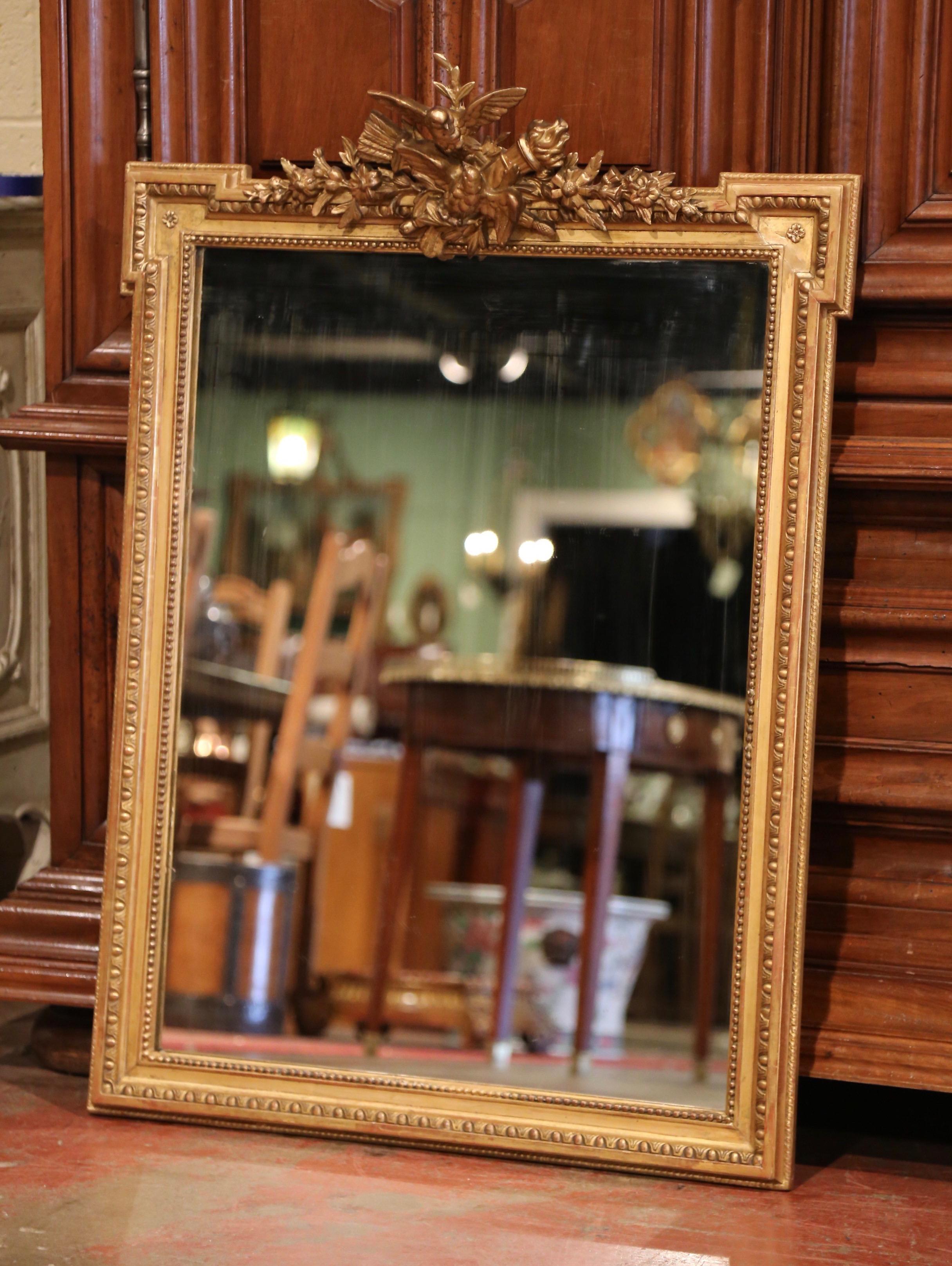 Decorate a powder room or an entry way with this elegant antique mirror; crafted in France circa 1870, the rectangular mirror with recessed corners, features two carved birds at the pediment embellished with crossed torches and flanked with floral