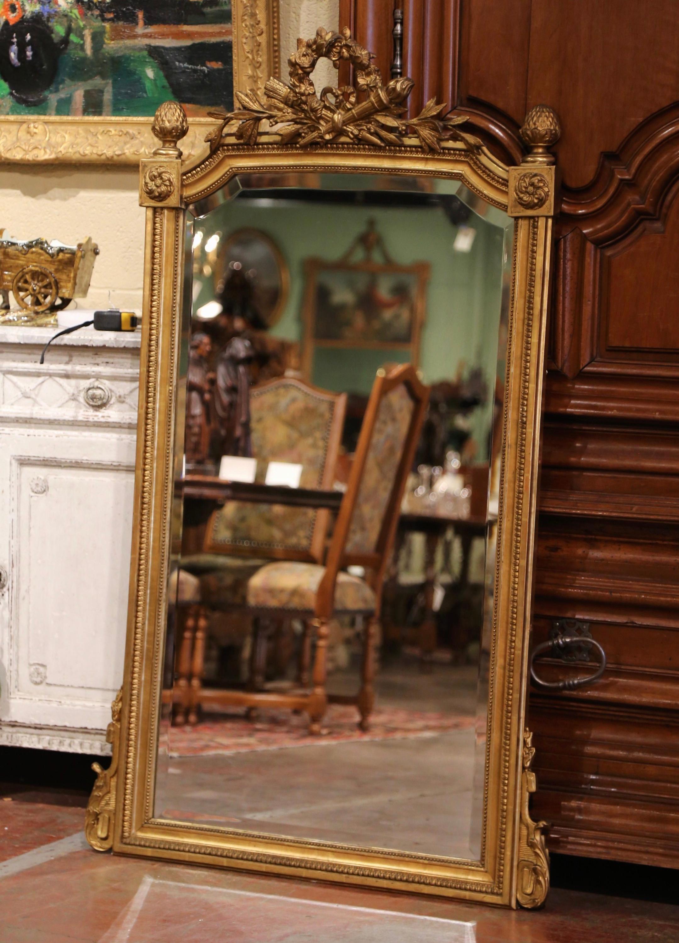 Decorate a powder room or an entry way with this elegant and tall antique mirror! Crafted in France circa 1870, the rectangular mirror with curved top and concave corners, features an intricate cartouche at the pediment embellished with crossed