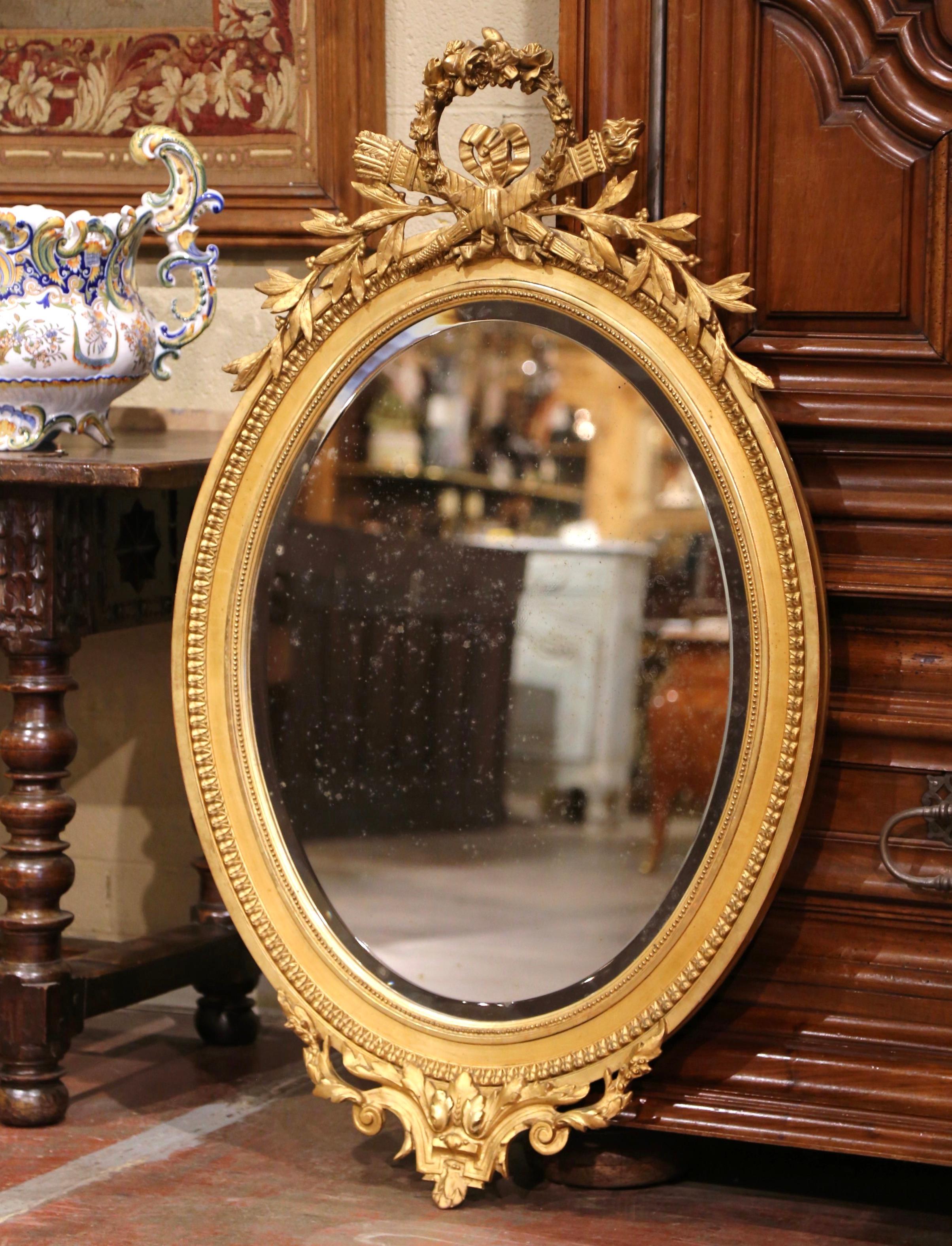 Dekorieren Sie eine Nasszelle oder den Eingangsbereich mit diesem eleganten antiken vergoldeten Wandspiegel. Der um 1870 in Frankreich gefertigte ovale Perlenrahmen ist am Giebel mit einer großen Kartusche mit floralen Motiven, Fackeldekor und