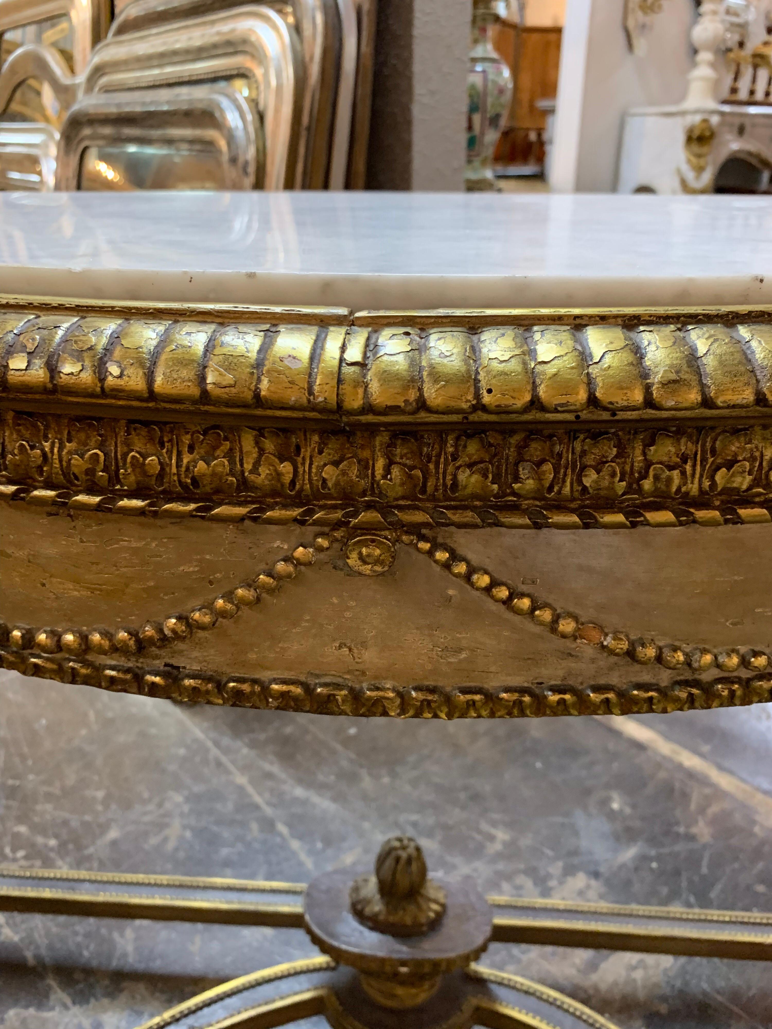 19th century Louis XVI carved demilune parcel gilt console table. The table is beautifully carved and has a Carrera marble top. Classic French style and quality make this a wonderful addition to any fine home.