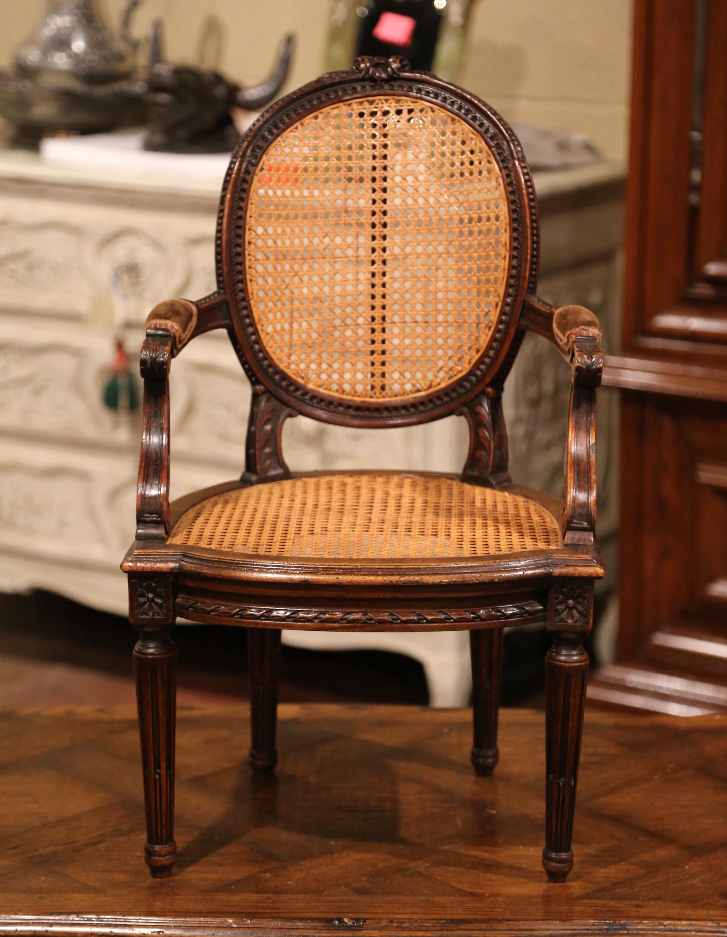 Add charm to a family friendly living room or nursery with this elegant kids armchair. Crafted in France circa 1860 and heavily carved, the antique chair stands on tapered and fluted legs decorated with floral medallions at the shoulder; the