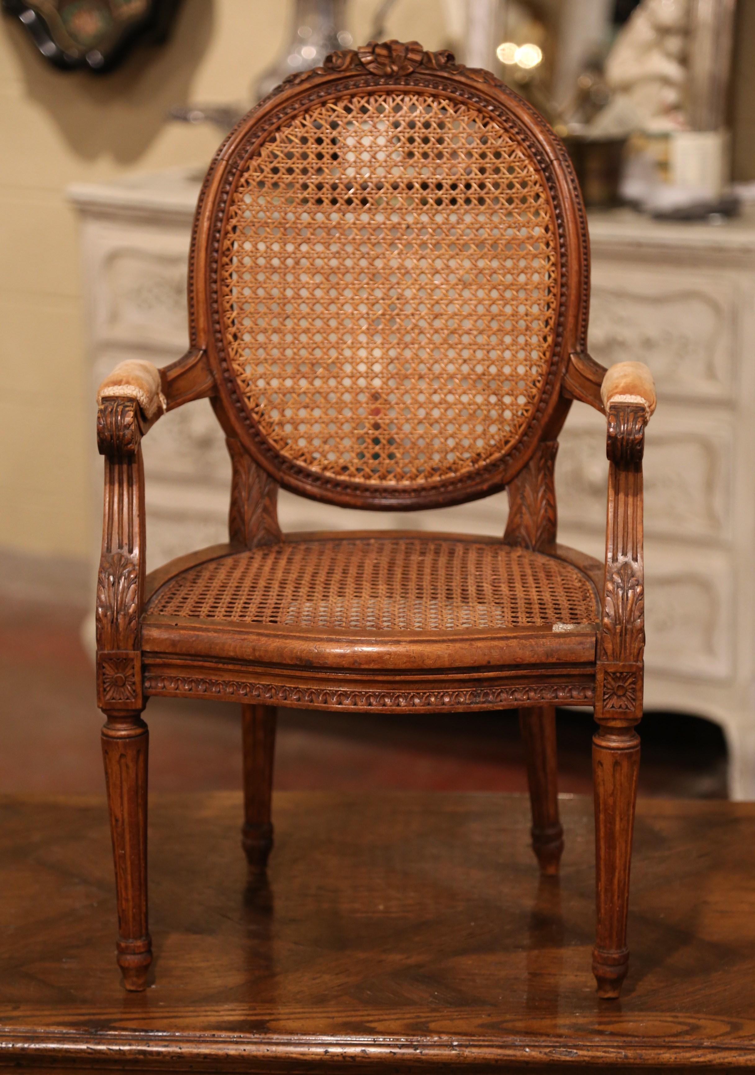 Add charm to a family friendly living room or nursery with this elegant kids armchair. Crafted in France circa 1860 and heavily carved, the antique chair stands on tapered and fluted legs decorated with floral medallions at the shoulder; the