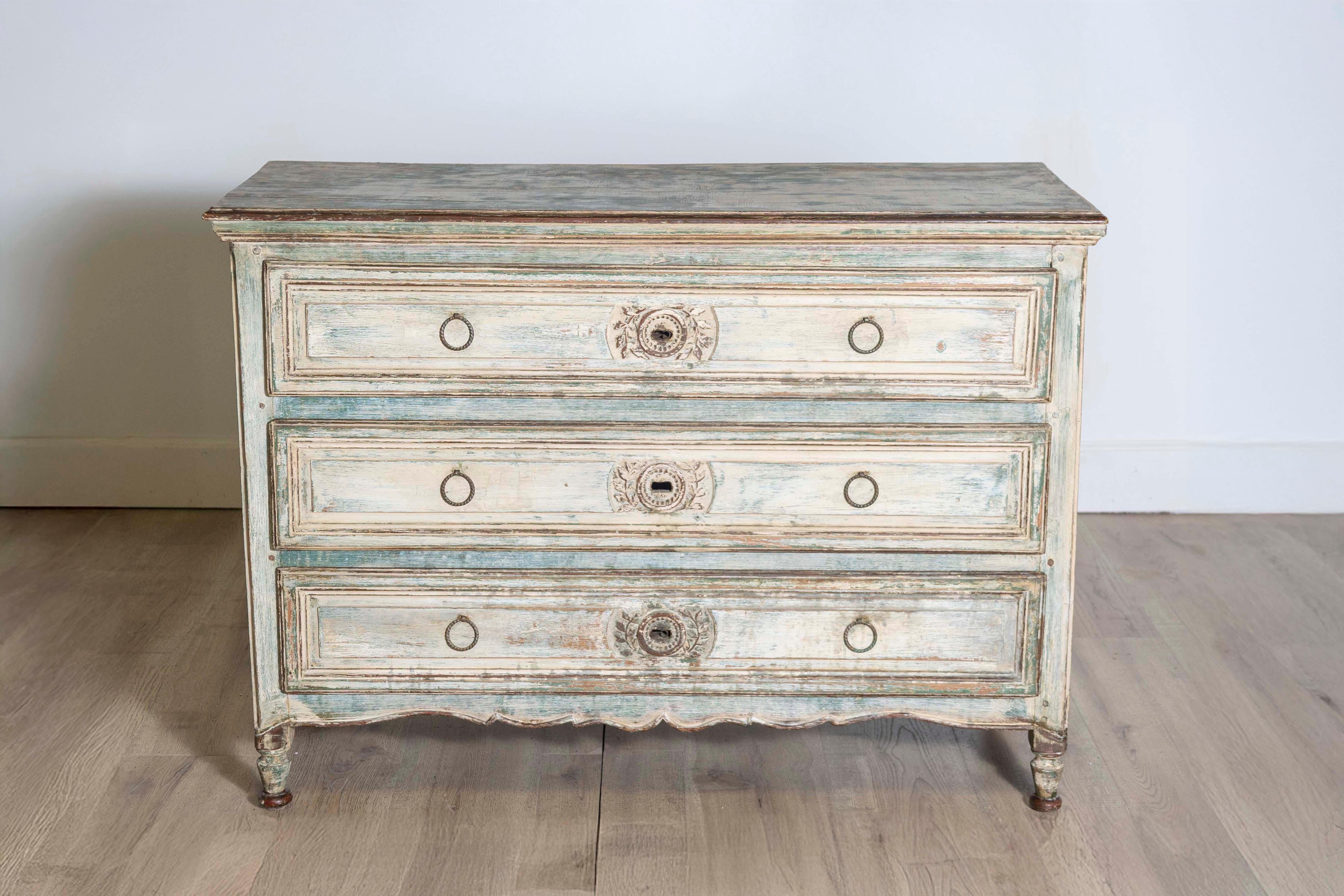 This elegant 19th century French Louis XVI commode, crafted in bleached oak, is a timeless testament to neoclassical design. With three spacious drawers adorned with delicate floral and leaf carving motifs, it embodies the refined artistry and