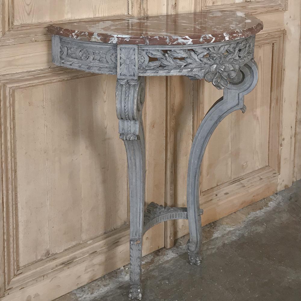 19th Century French Louis XVI Demilune Marble Top Console is a timeless example of neoclassical splendor, with intricate detail carved across the entire apron and on the gracefully scrolled legs, all enhanced by the patinaed painted finish.  The