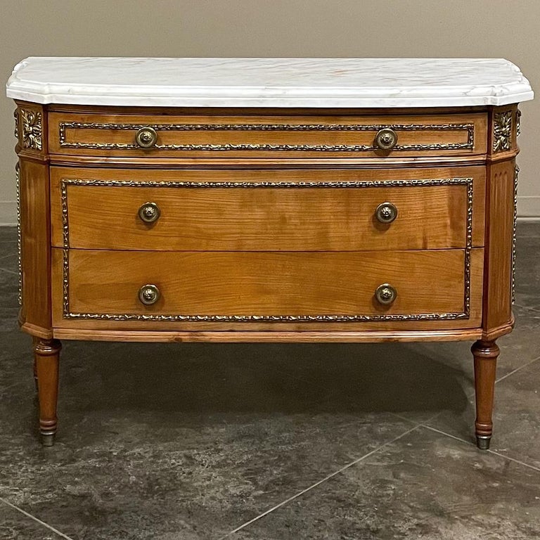 19th century French Louis XVI fruitwood marble top commode is a highly unusual iteration of the form, blending the luxurious naturalism of Carrara marble with the luster of cast & burnished bronze with the natural color of fine French fruitwood! The