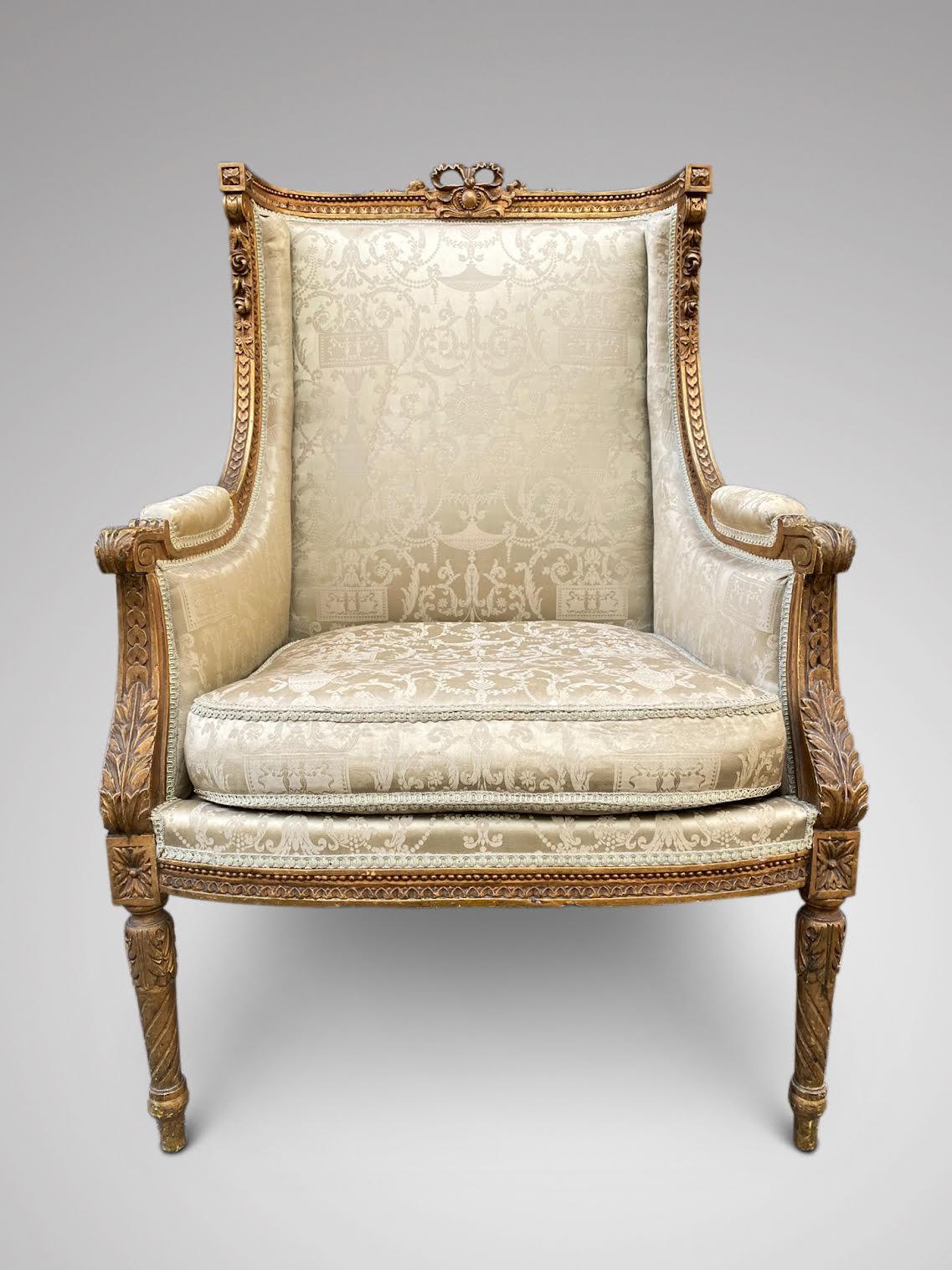 A late 19th century French Louis XVI Style gold gilt wood square back wingback bergère armchair. This chair has hand carved, acanthus and geometric accents with neoclassical details, florals and fluted legs in gilt wood finish with the original silk