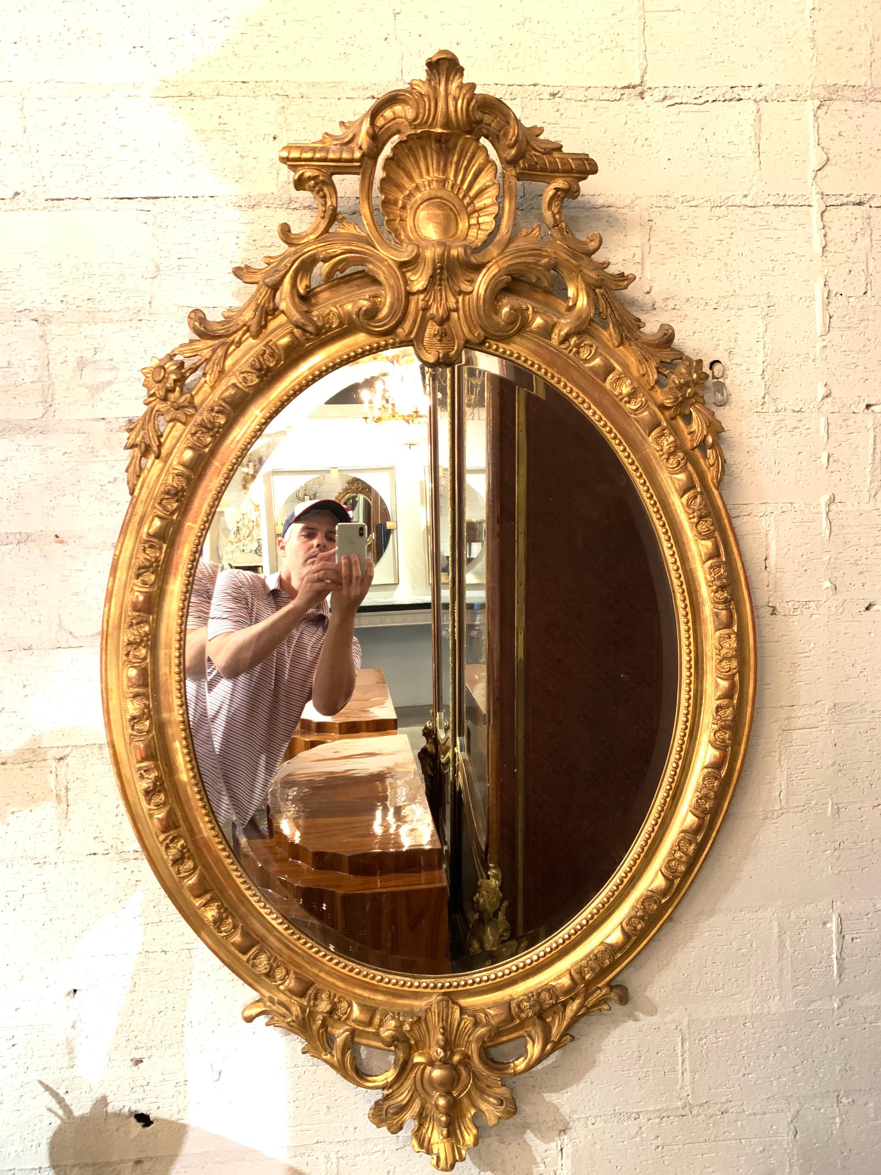 Beautiful 19th century French Louis XVI giltwood and gesso oval mirror. Exceptional details including a crest, floral images and beaded border. Very fine quality!
