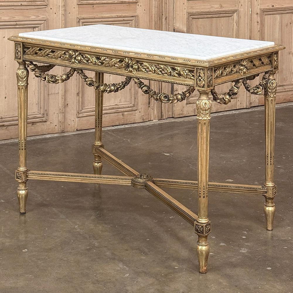 La mesa de centro de madera dorada Luis XVI francesa del siglo XIX con mármol de Carrara se diseñó para dar un gran impacto visual a la habitación.  El diseño, útil en diversos entornos, incluidas las entradas para lograr el máximo efecto, se cubrió